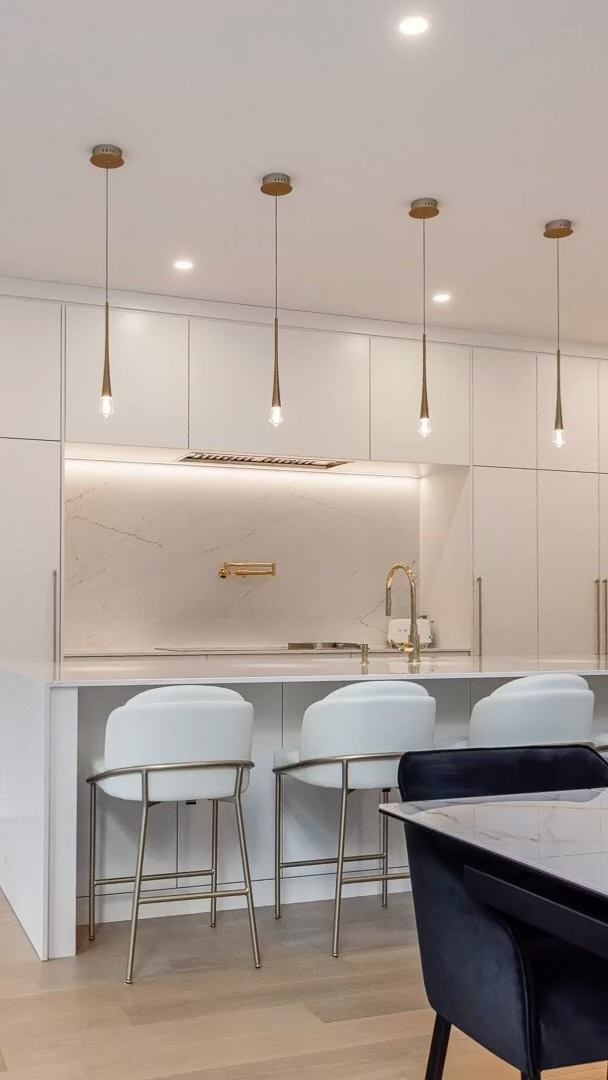 Explore this elegant modern kitchen featuring sleek white cabinetry and warm pendant lighting, perfect for cooking and entertaining.