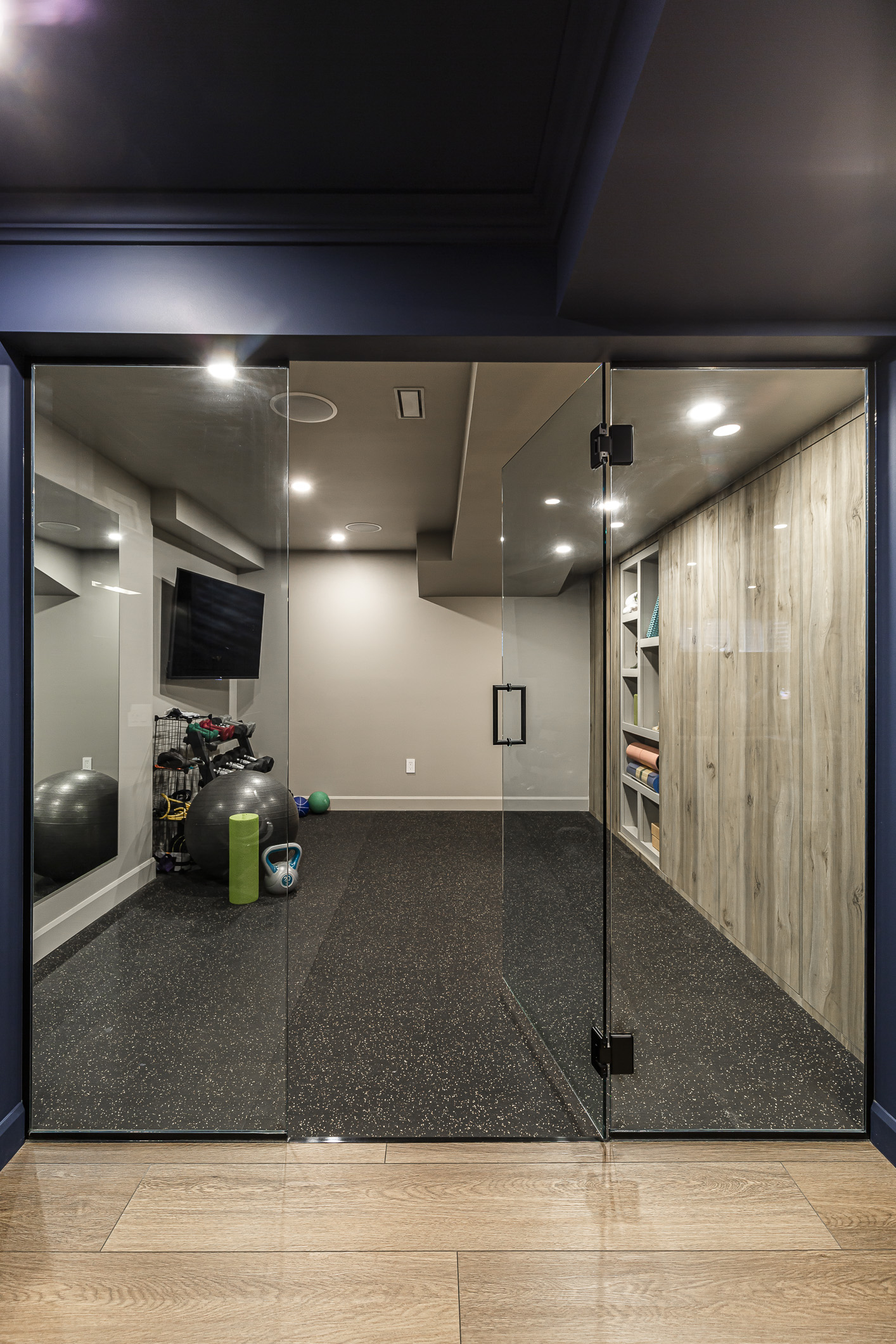 Stylish basement recreation and gym area with modern decor, fitness equipment, and ample natural light.