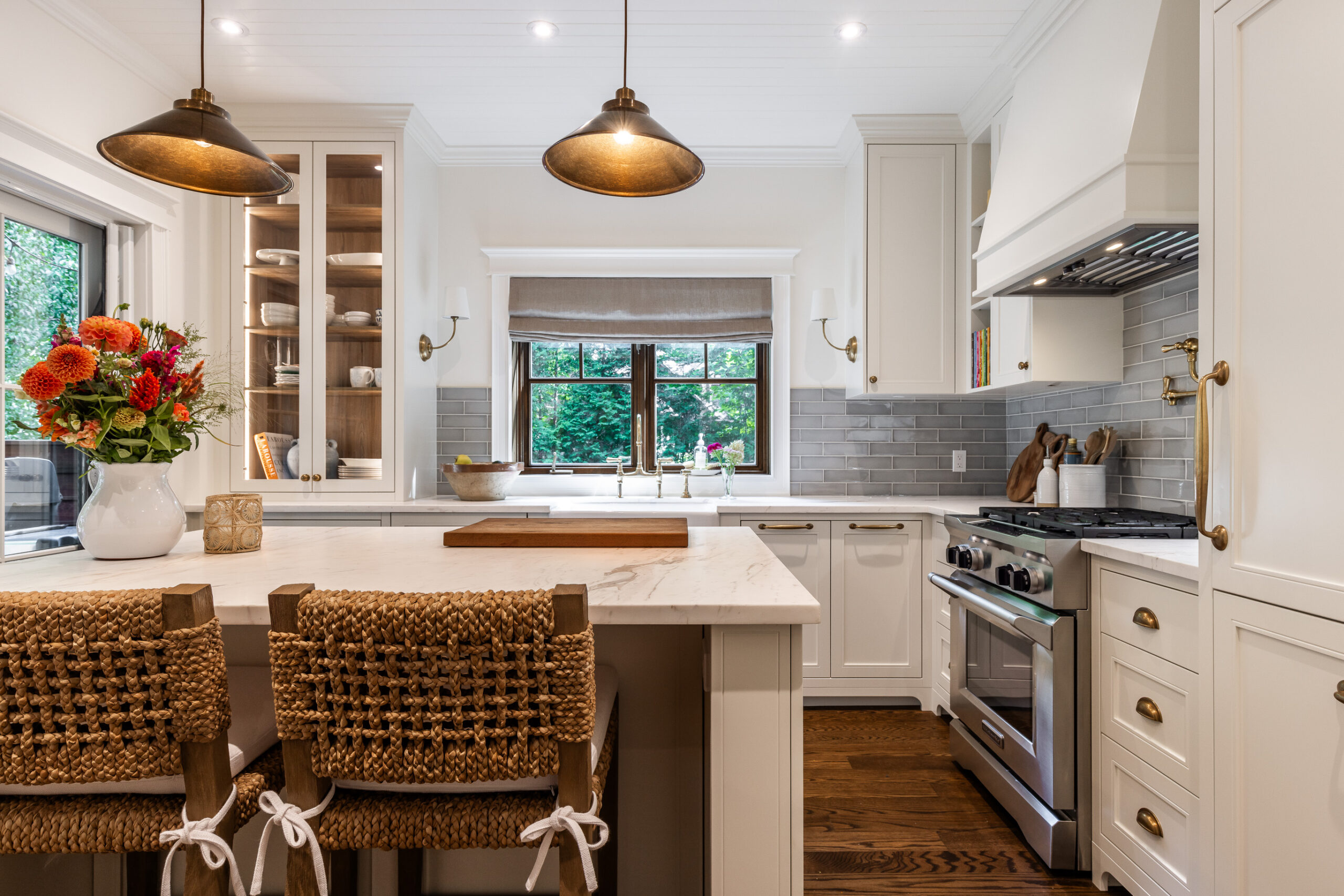 Experience the harmony of light and warmth in this modern kitchen, featuring white cabinetry, stylish island seating, and elegant natural elements.