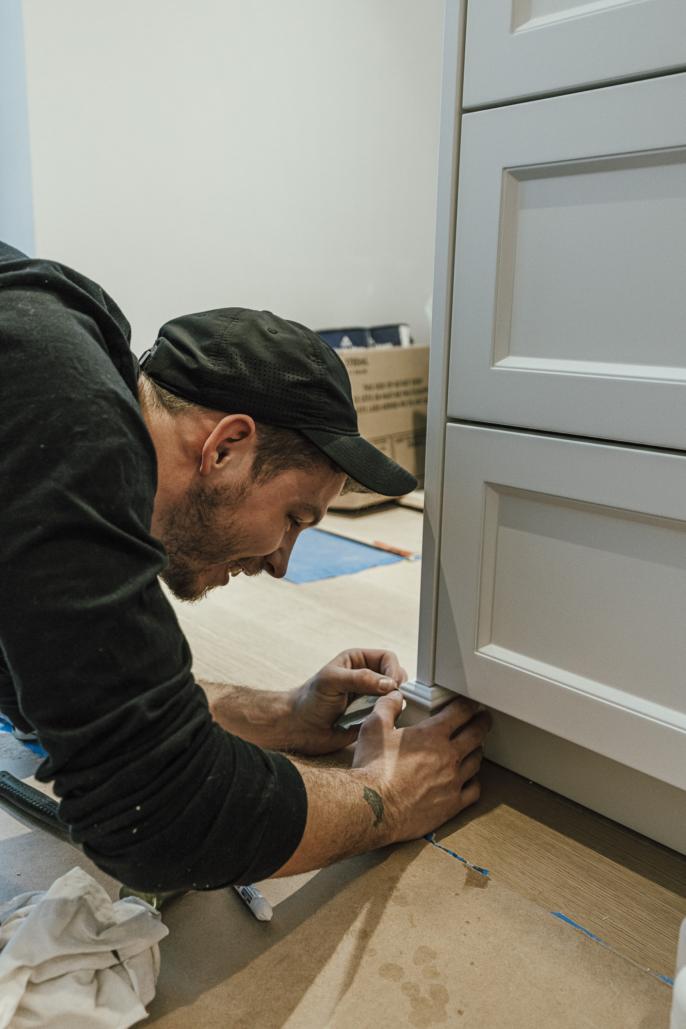 A focused handyman installs sleek white cabinets in a bright kitchen, showcasing skill and dedication in home renovation.