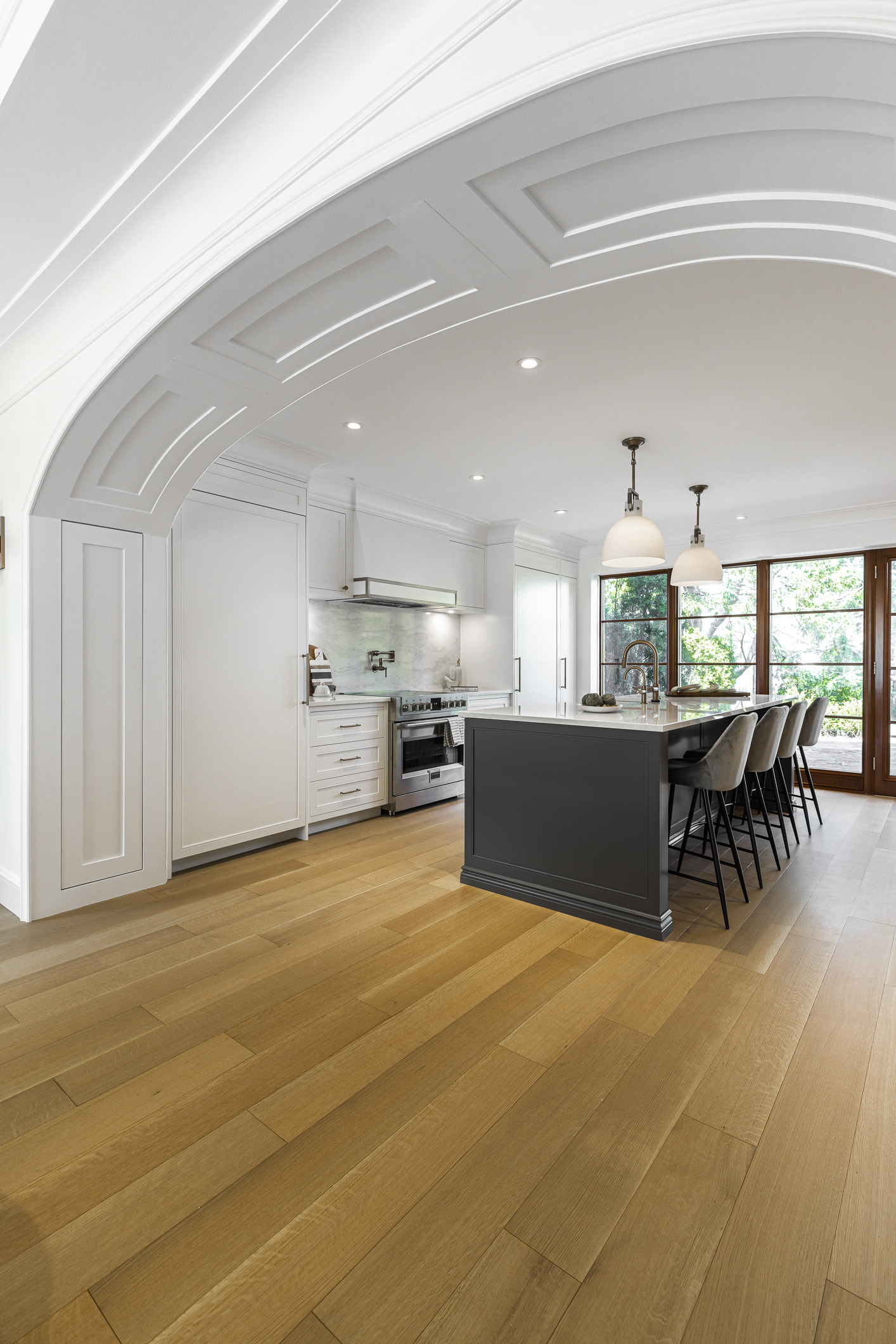 Experience the elegance of this modern kitchen featuring a sleek gray island, white cabinetry, and abundant natural light for a welcoming atmosphere.