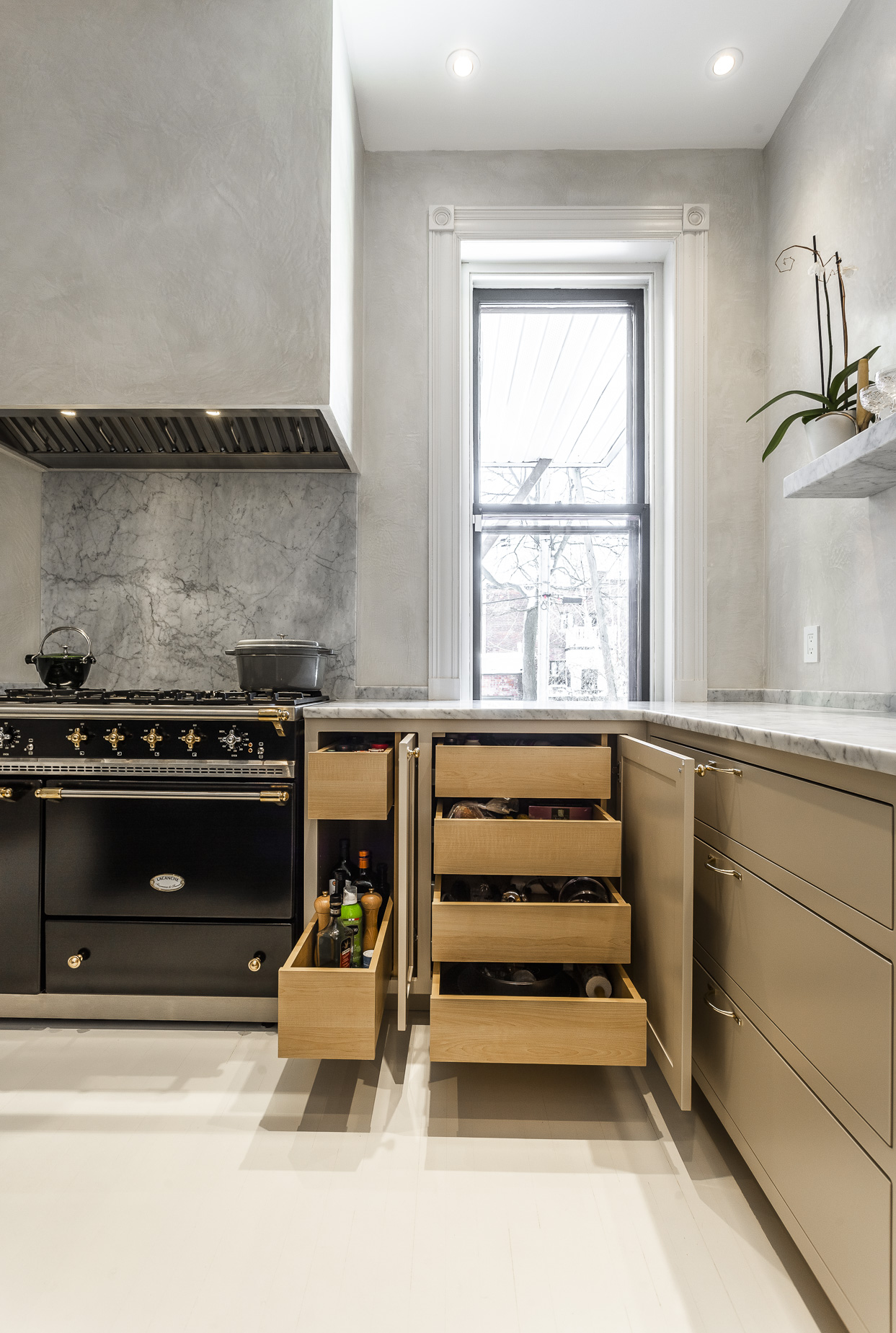 Modern kitchen featuring a sleek gray backdrop, a striking black range, and abundant natural light for a warm, inviting atmosphere.