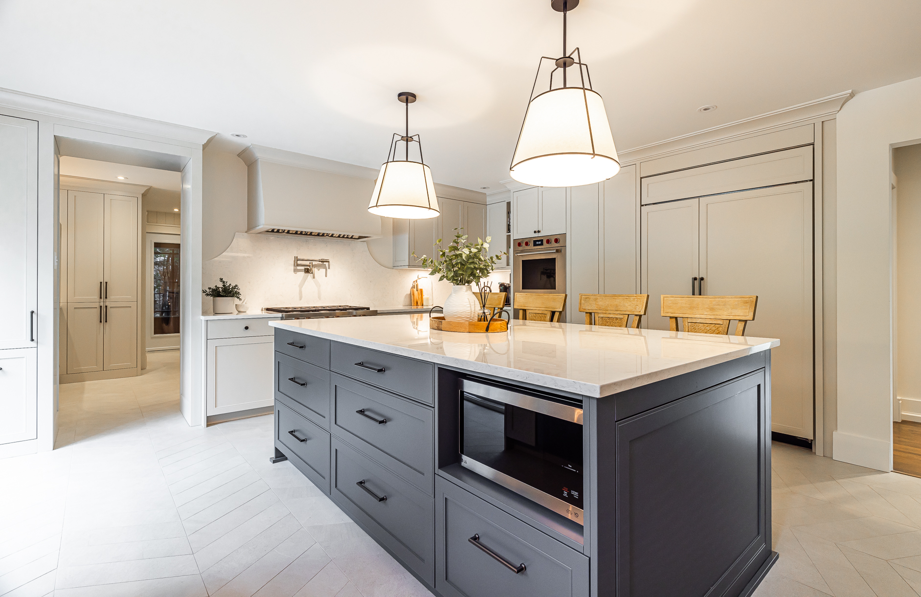 Chic modern kitchen with gray island, light stone countertop, and elegant pendant lighting.