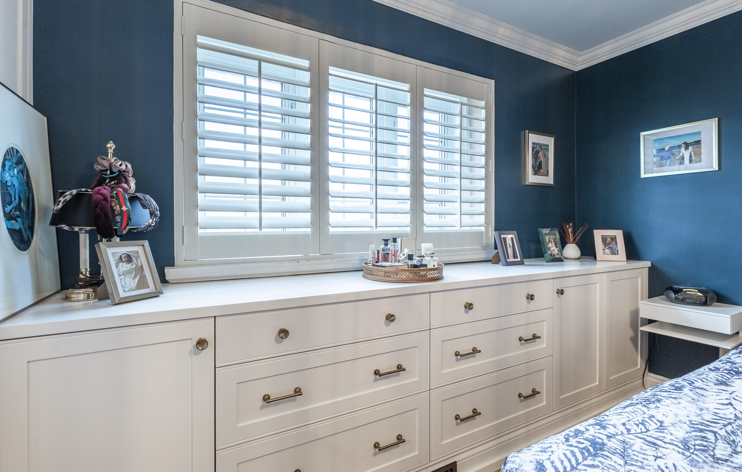 A serene bedroom features deep blue walls, a stylish white dresser, and cozy decor, creating an inviting retreat for relaxation.
