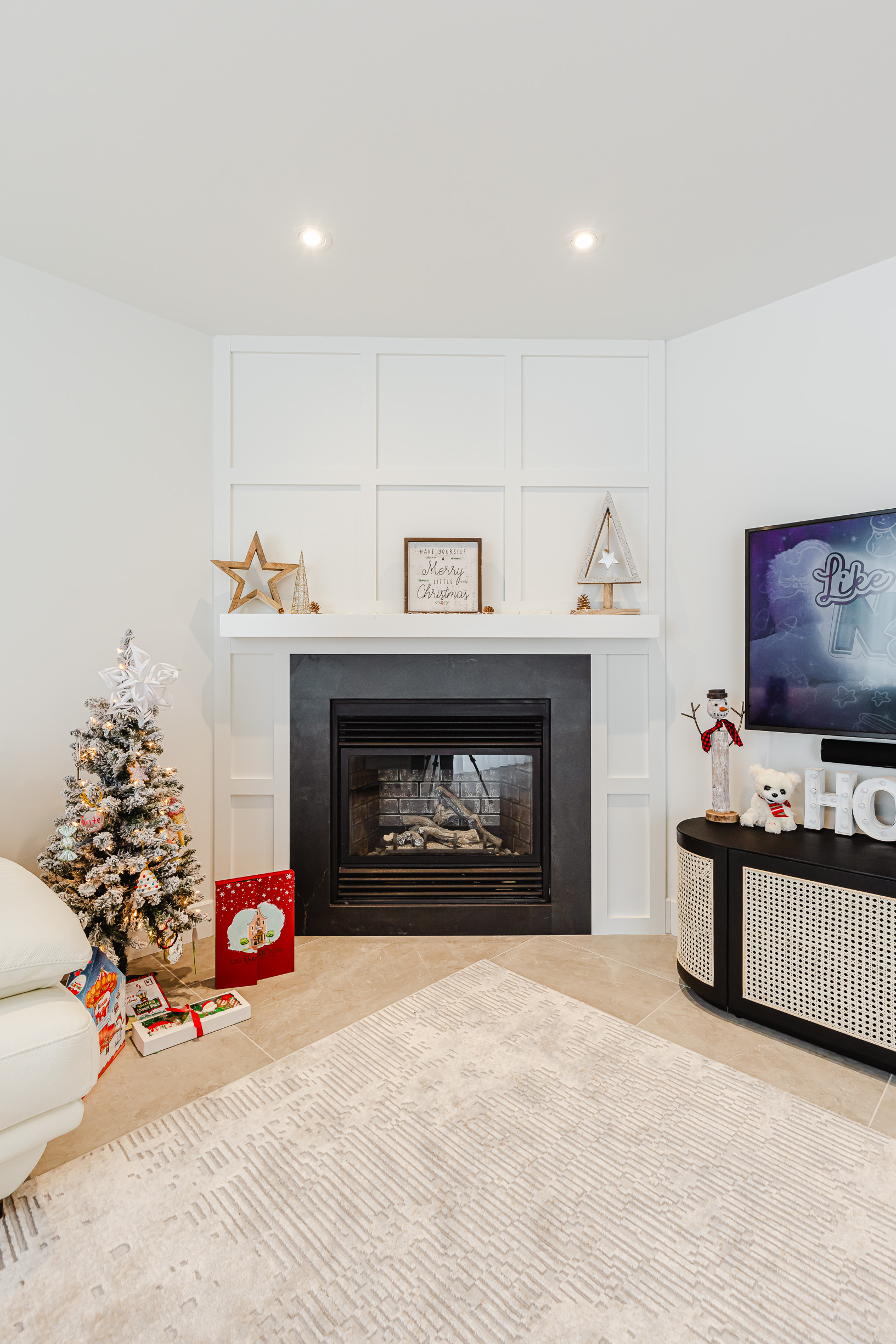 Cozy holiday living room with a modern fireplace and beautifully decorated Christmas tree.