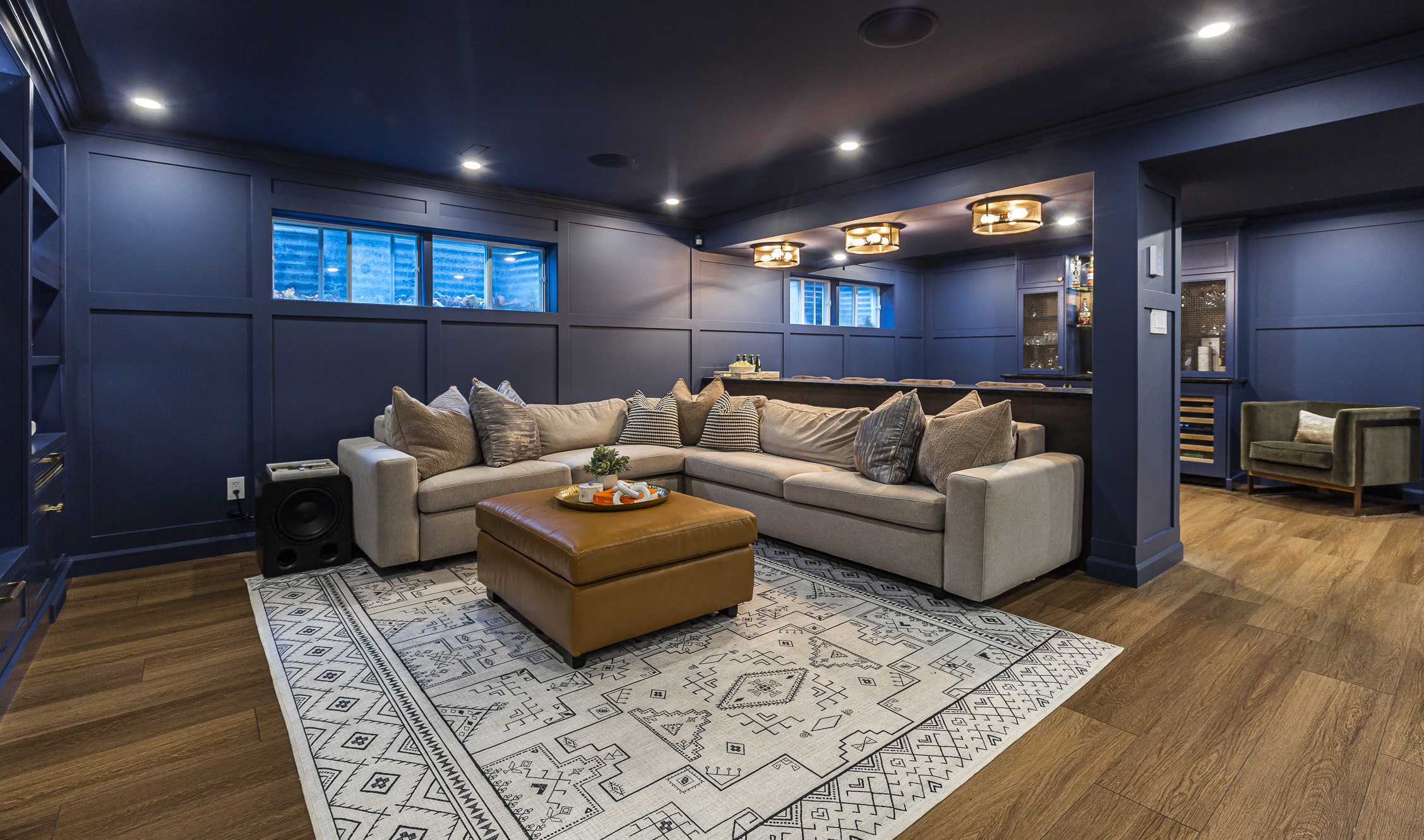 Stylishly cozy living room with navy walls, a light sectional sofa, and a warm wooden coffee table, inviting relaxation and entertainment.