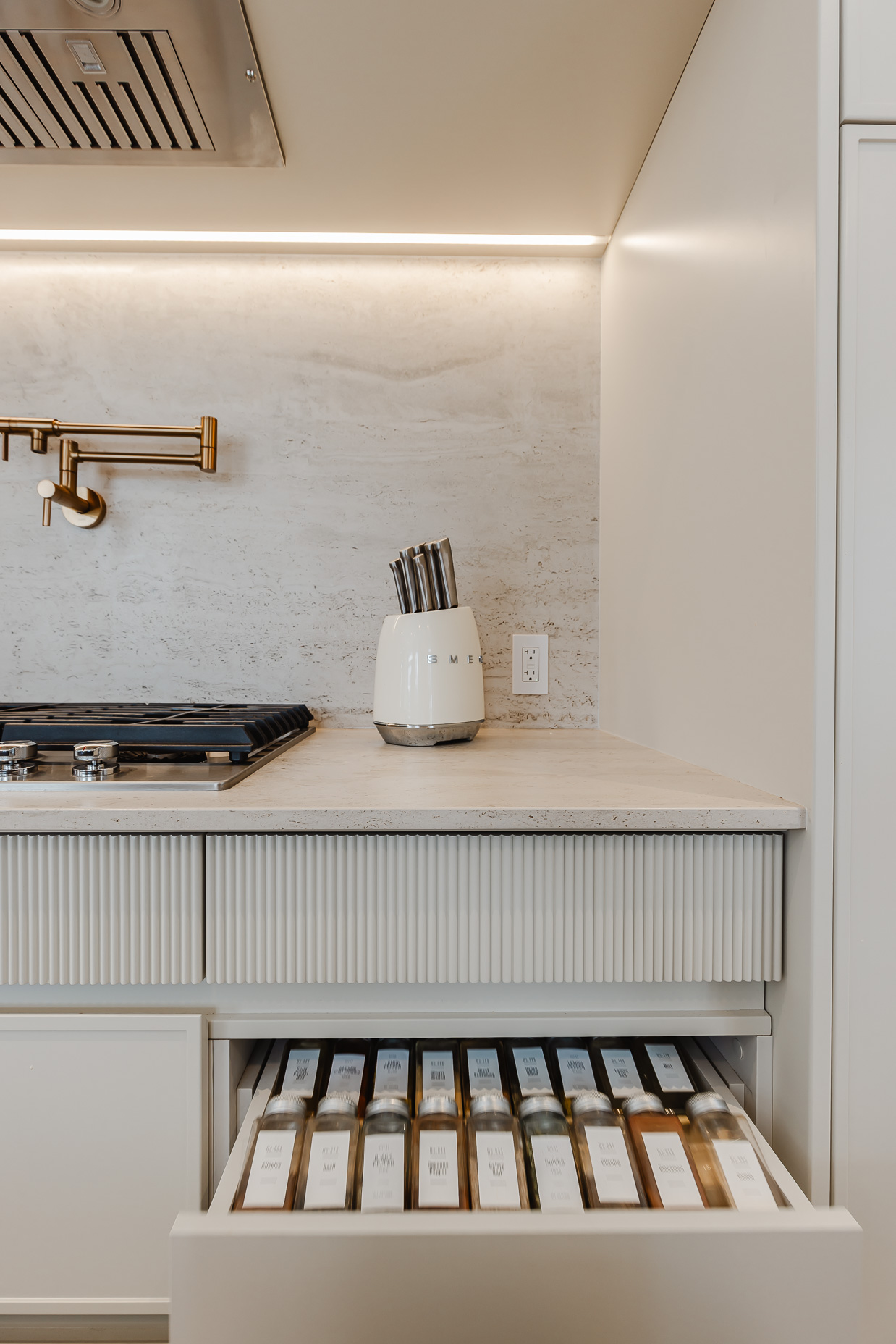 Discover a stylish minimalist kitchen featuring a spacious island, elegant brass accents, and inviting under-cabinet lighting.