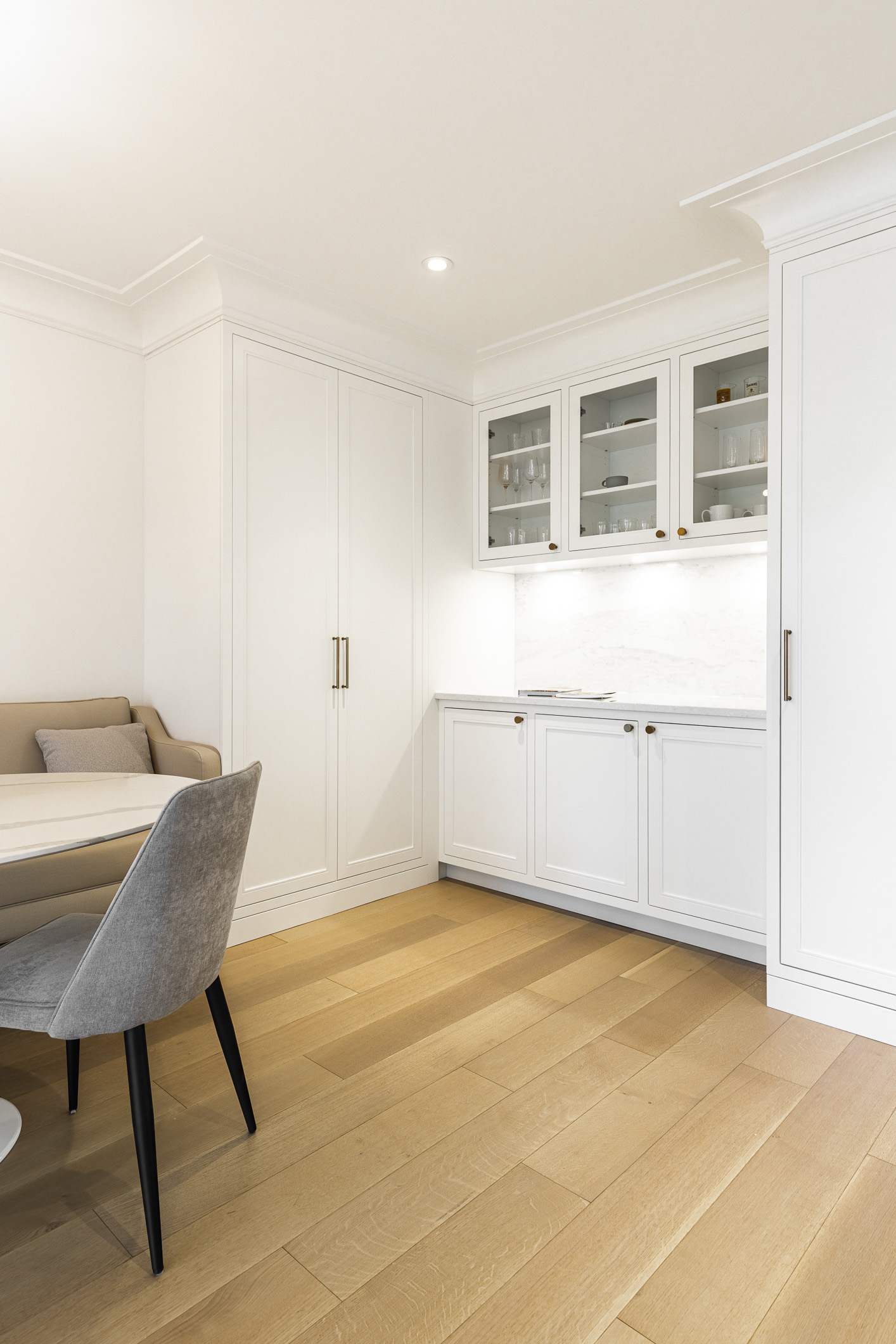 Bright and airy minimalist kitchen with elegant white cabinetry, gold accents, and a cozy dining nook for delightful gatherings.