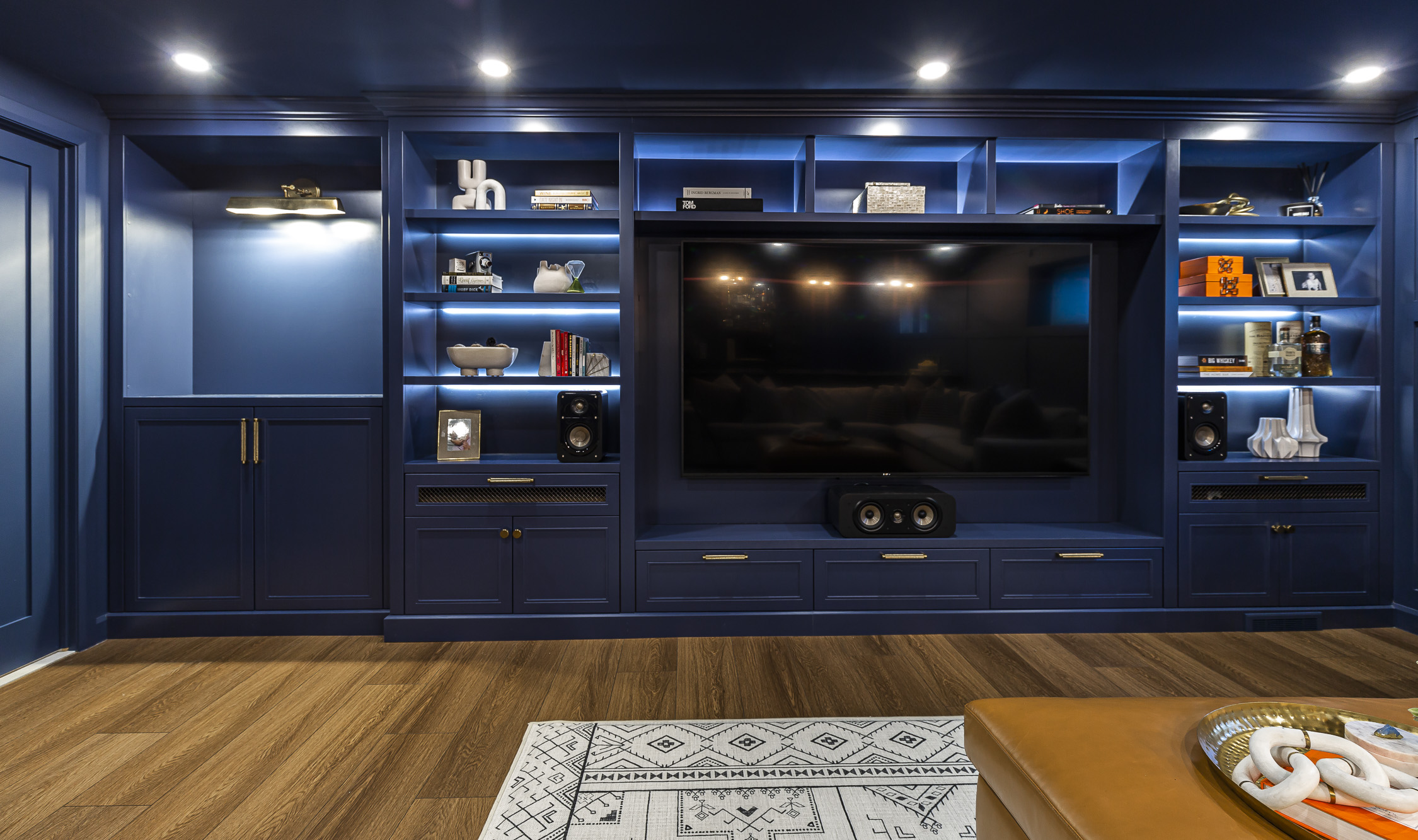 Contemporary entertainment area with navy blue accents, sleek shelving, and inviting light wood flooring.