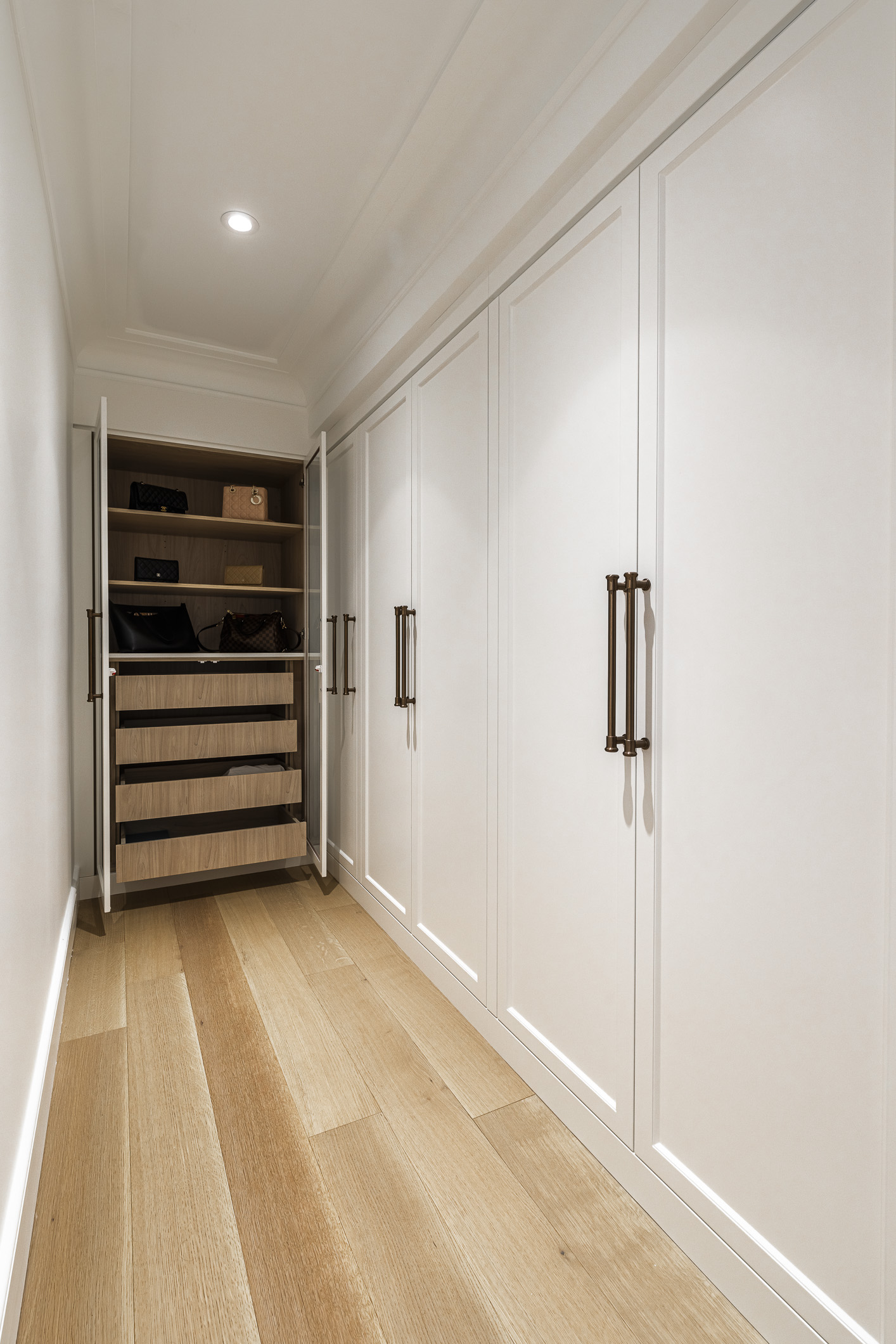 Discover a modern hallway featuring sleek built-in cabinets, warm wooden flooring, and inviting recessed lighting for a stylish and organized space.