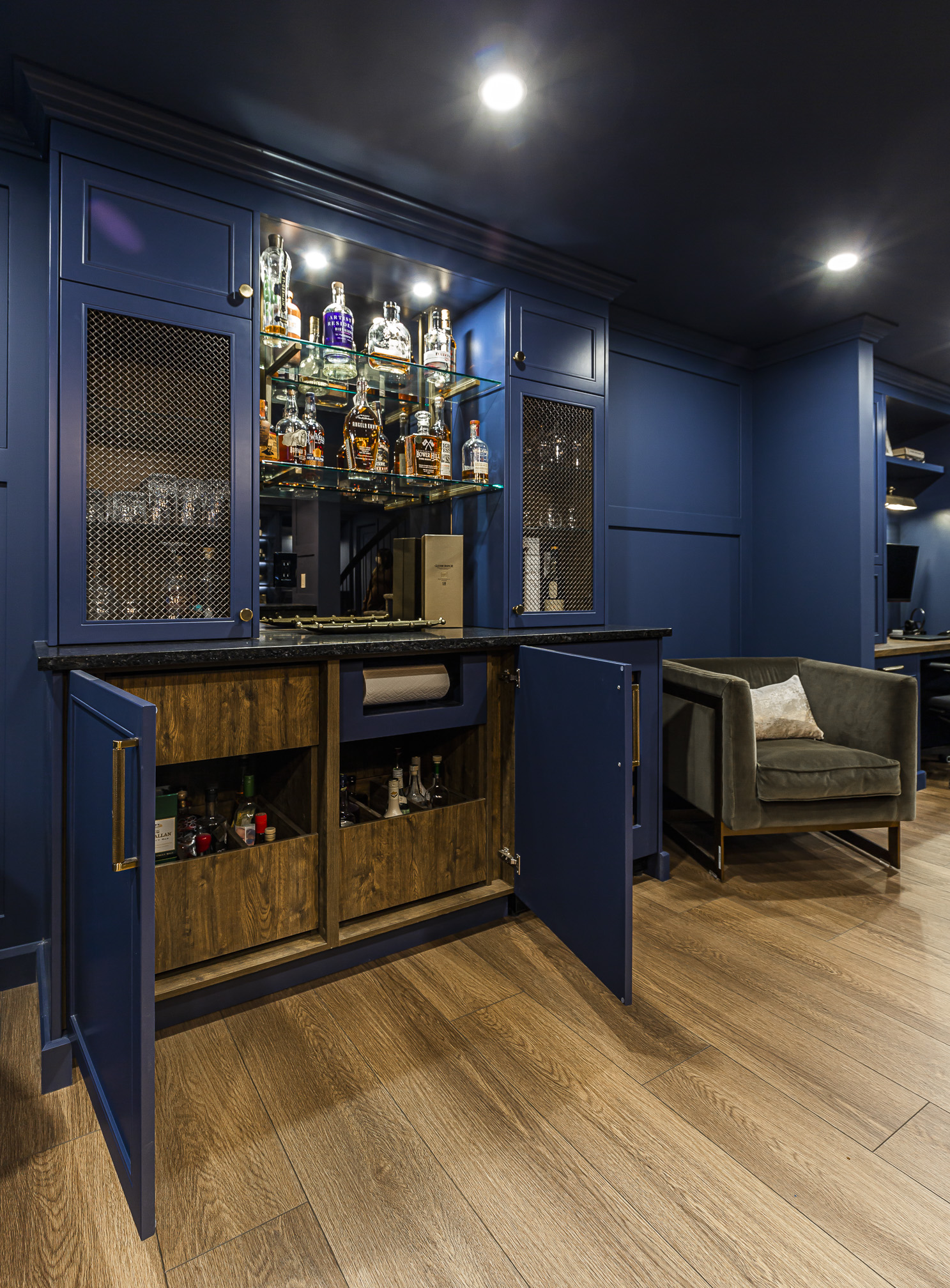 Savor elegance in this home bar featuring deep blue cabinetry, chic seating, and inviting ambient lighting for the perfect entertaining space.