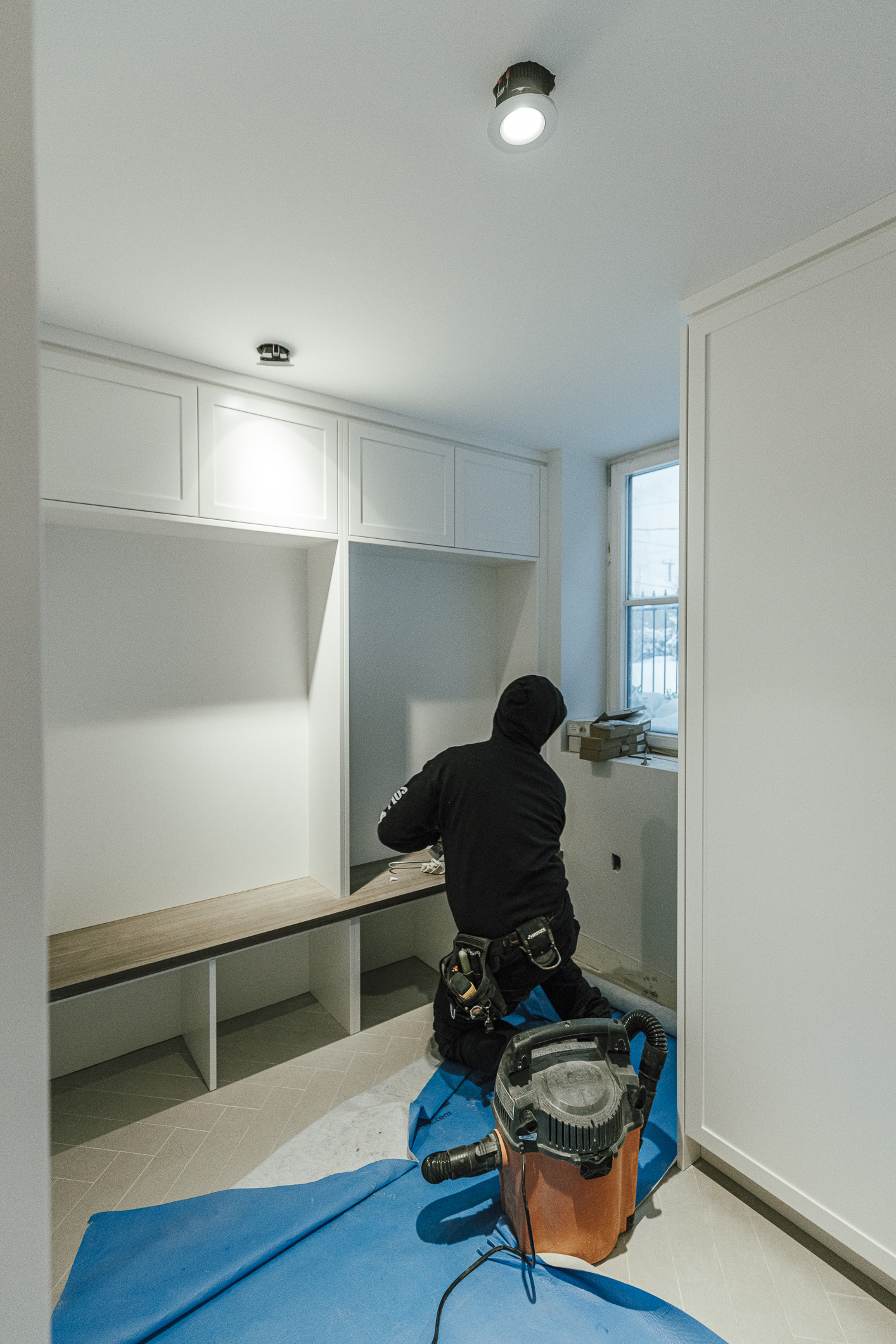 A skilled DIY enthusiast installs cabinetry in a bright, minimalist space, showcasing meticulous home renovation efforts.