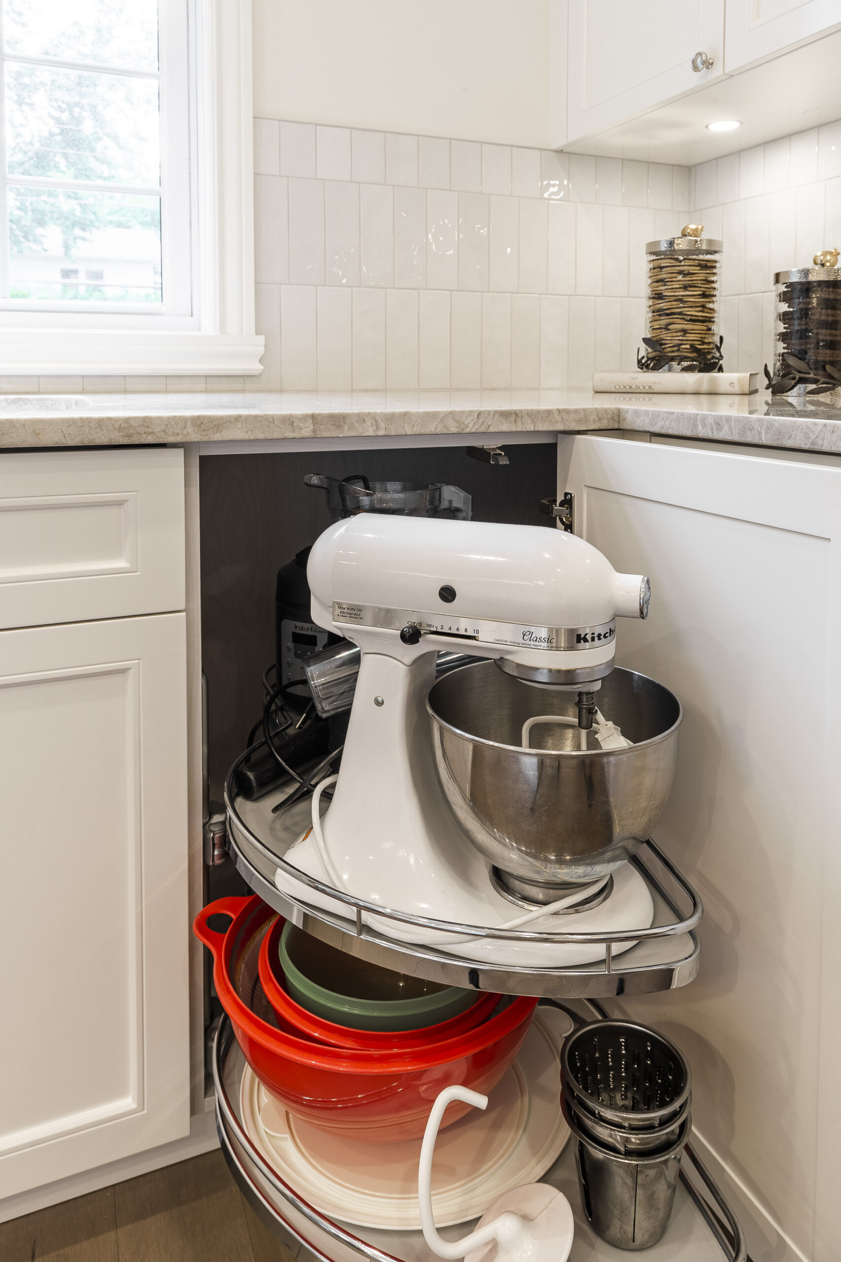 A modern kitchen corner features a sleek white stand mixer and vibrant mixing bowls, showcasing efficient organization and style for culinary enthusiasts.