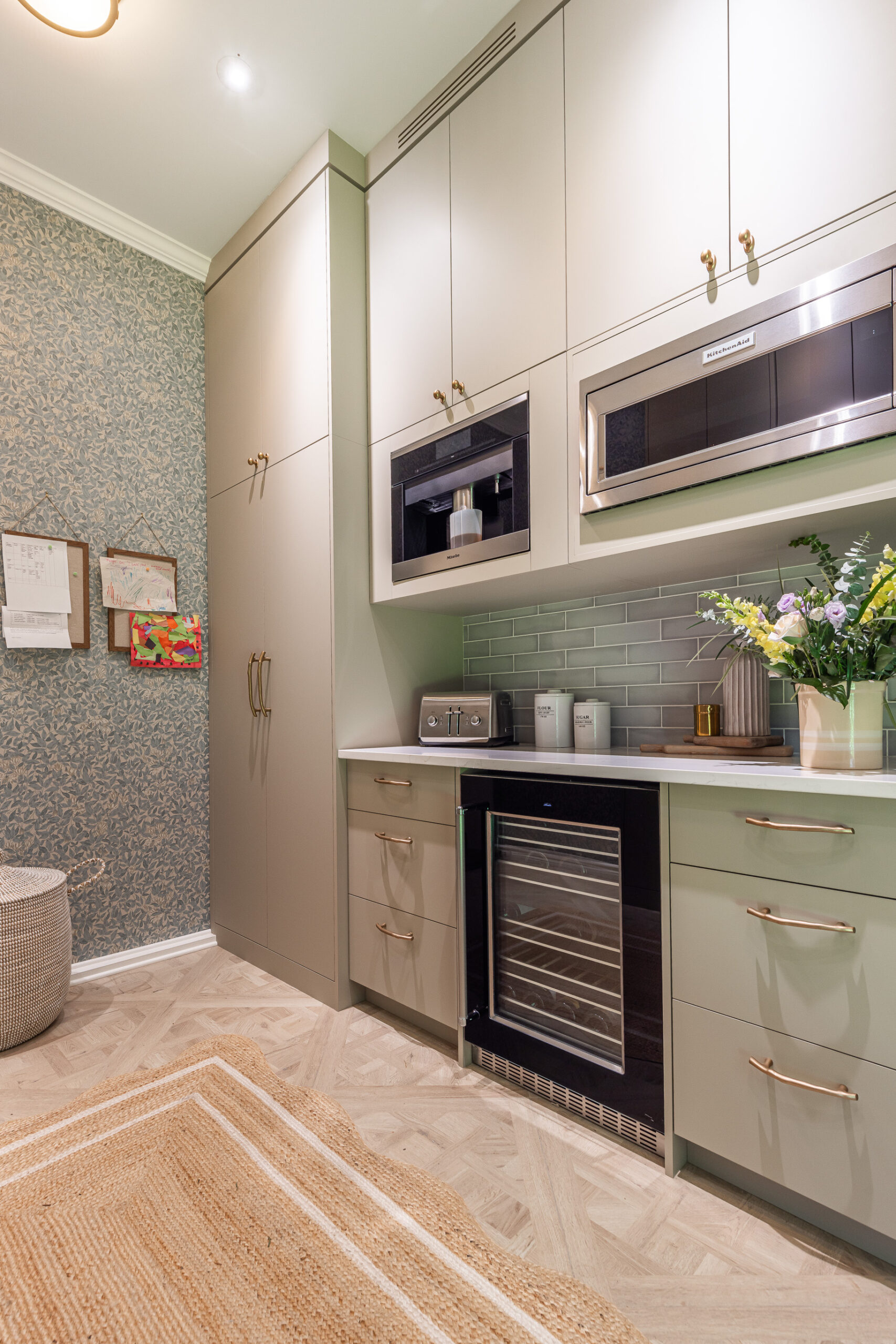 Discover a serene modern kitchen with muted green cabinetry, brass accents, and stylish decor that beautifully combines functionality and elegance.