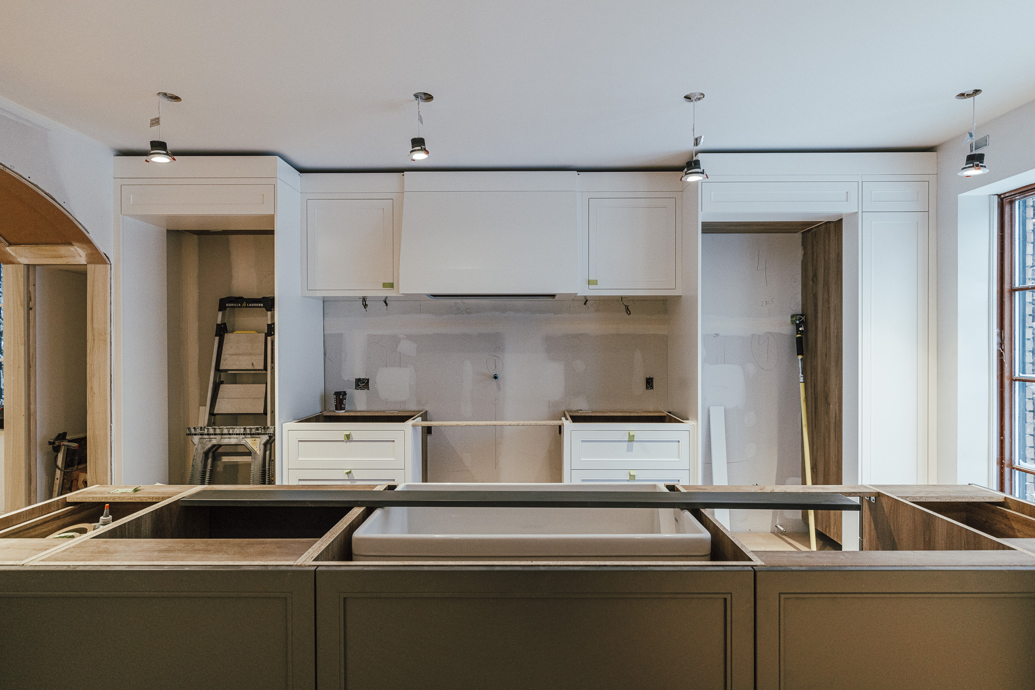 A modern kitchen renovation in progress showcases bright lighting, sleek cabinetry, and a central island ready for installation.