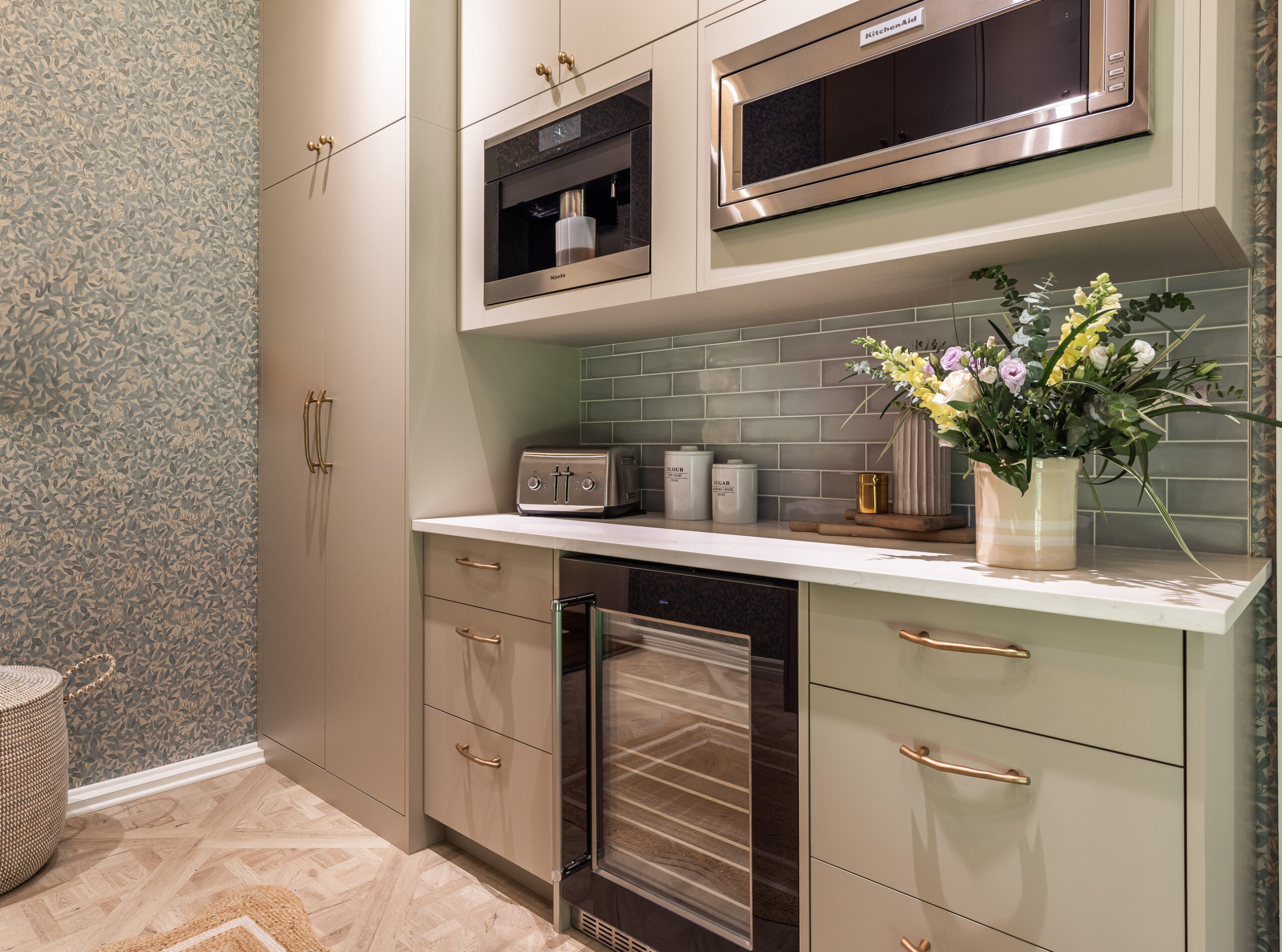 Discover a stylish modern kitchenette with green cabinetry, gold accents, and chic appliances, creating an inviting space for cooking and entertaining.
