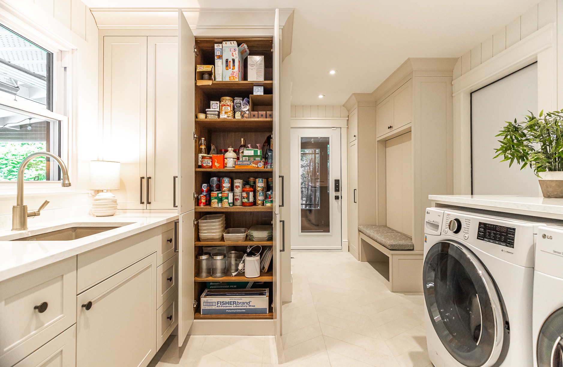 Bright and modern laundry room with stylish storage and functional appliances, featuring an inviting entryway bench for added comfort.