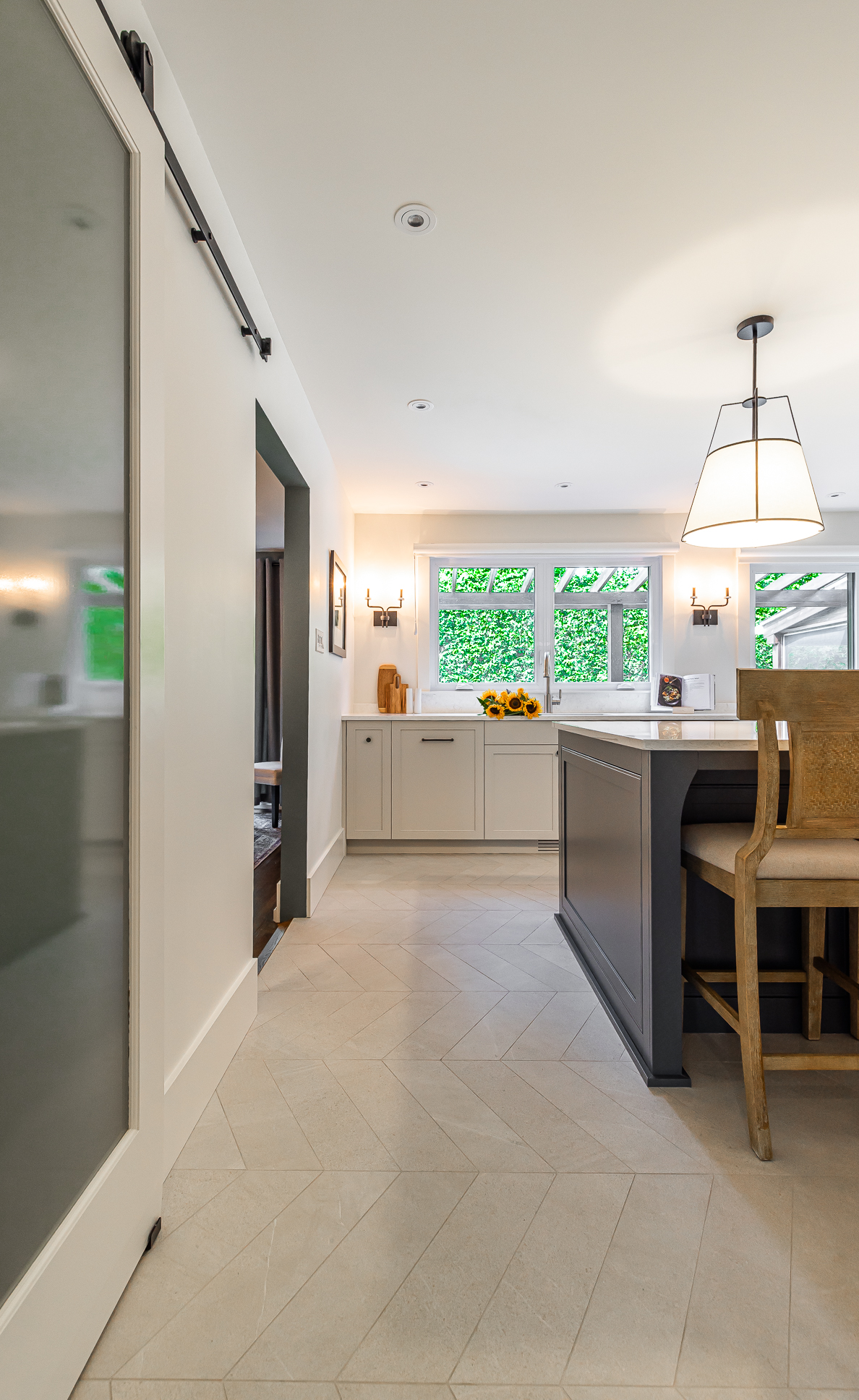 Bright and airy modern kitchen featuring rustic barstools, a sleek island, and a contemporary sliding barn door that enhances the inviting atmosphere.