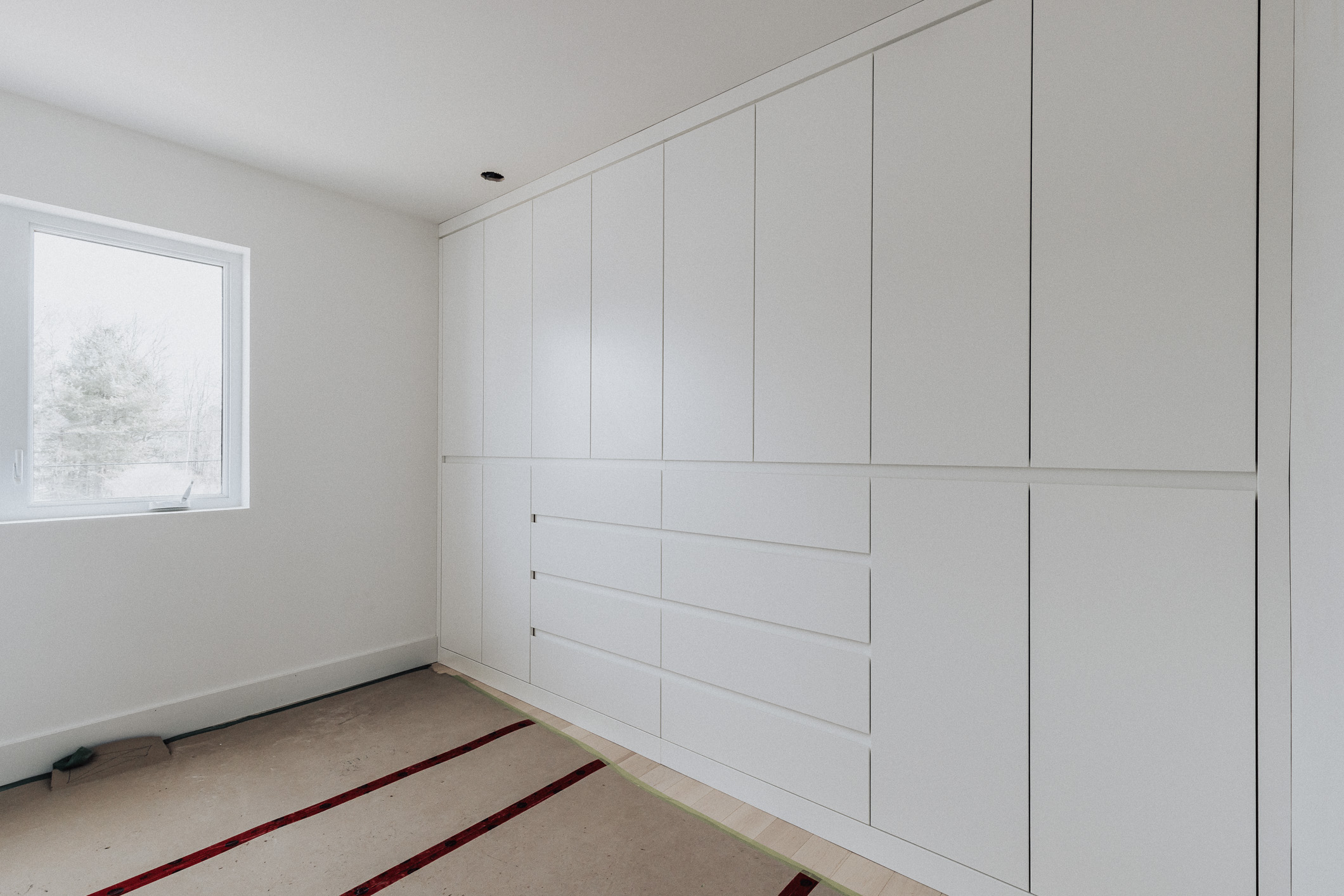 Bright and airy modern minimalist interior featuring ample built-in storage and a touch of nature from the window.