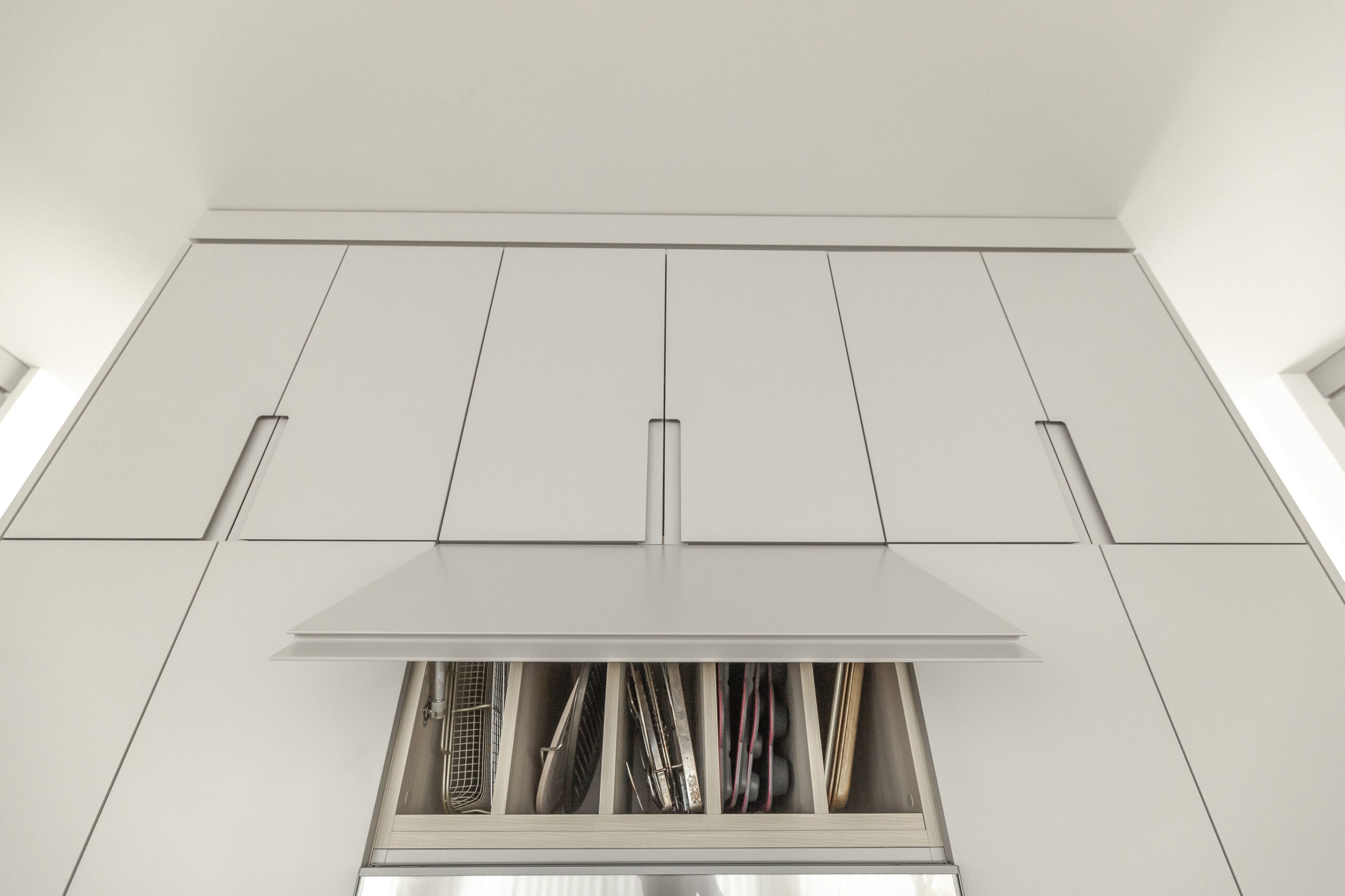Sleek white cabinets and a seamless range hood define this airy, functional minimalist kitchen, enhancing both style and usability.