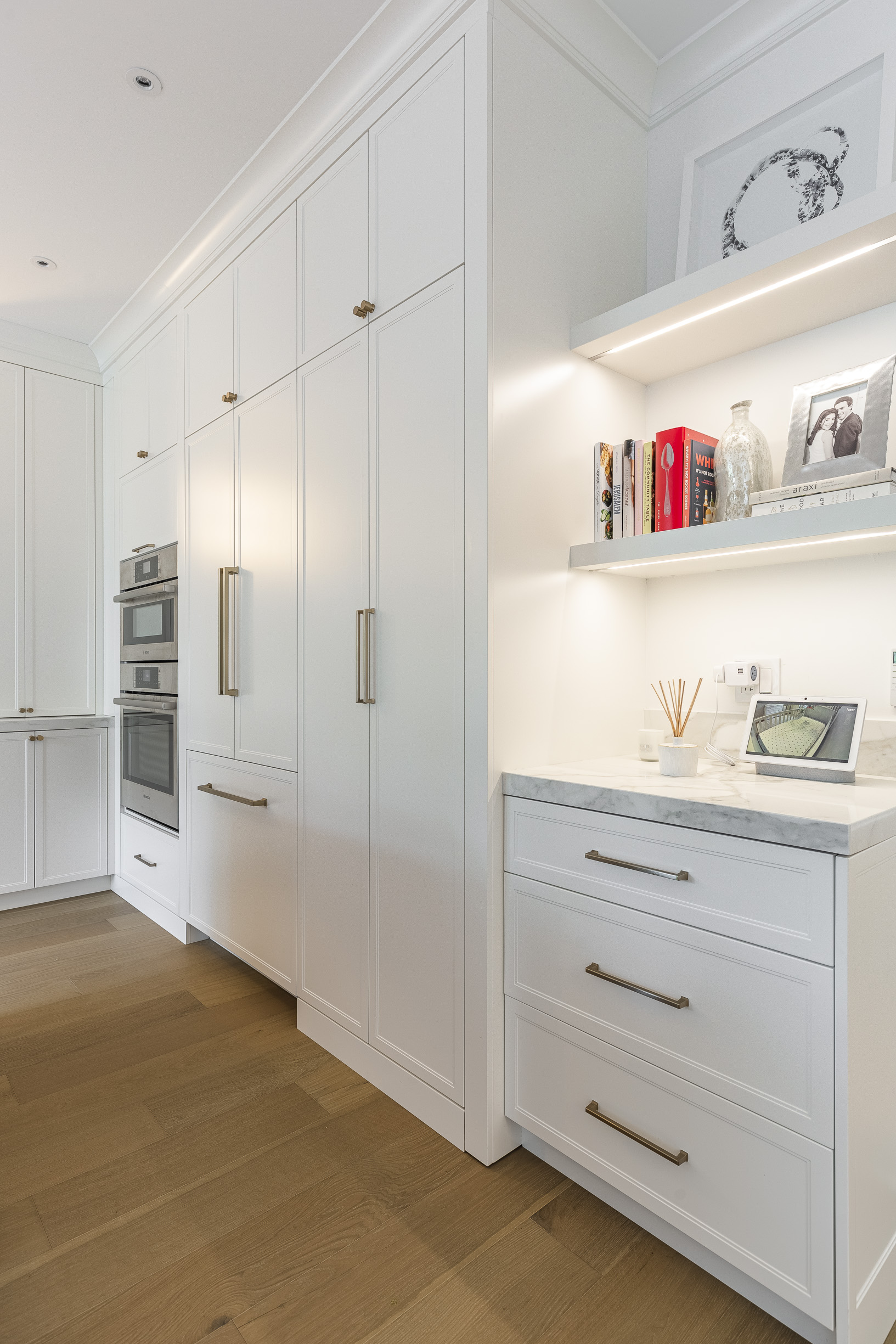 Bright and airy modern kitchen with sleek white cabinetry, stainless steel appliances, and personalized decor on open shelving.