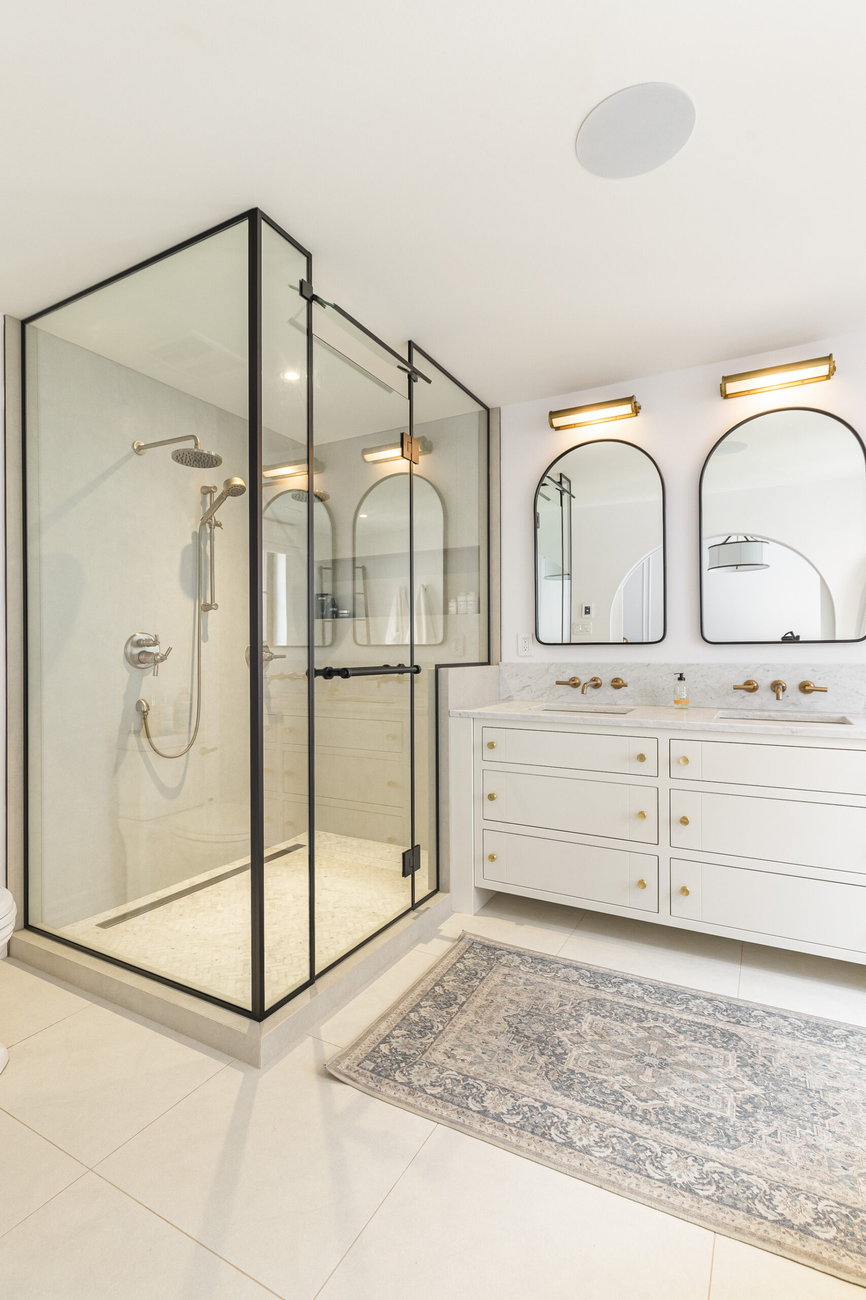 Experience elegance in a modern bathroom featuring a sleek glass shower, refined white vanity, and warm lighting for a serene ambiance.