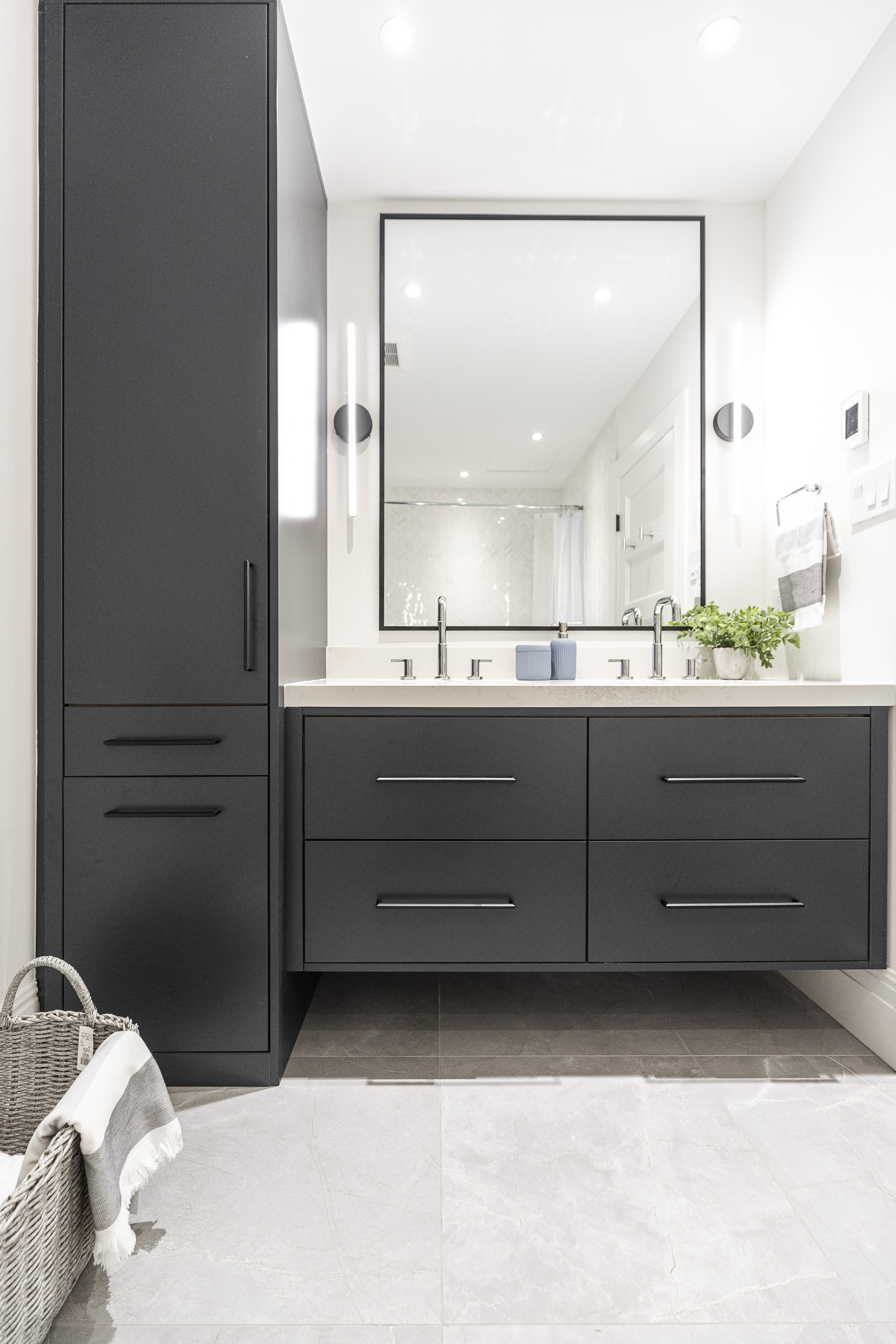 Explore this sleek black minimalist bathroom featuring ample storage, bright lighting, and inviting greenery for a modern touch.