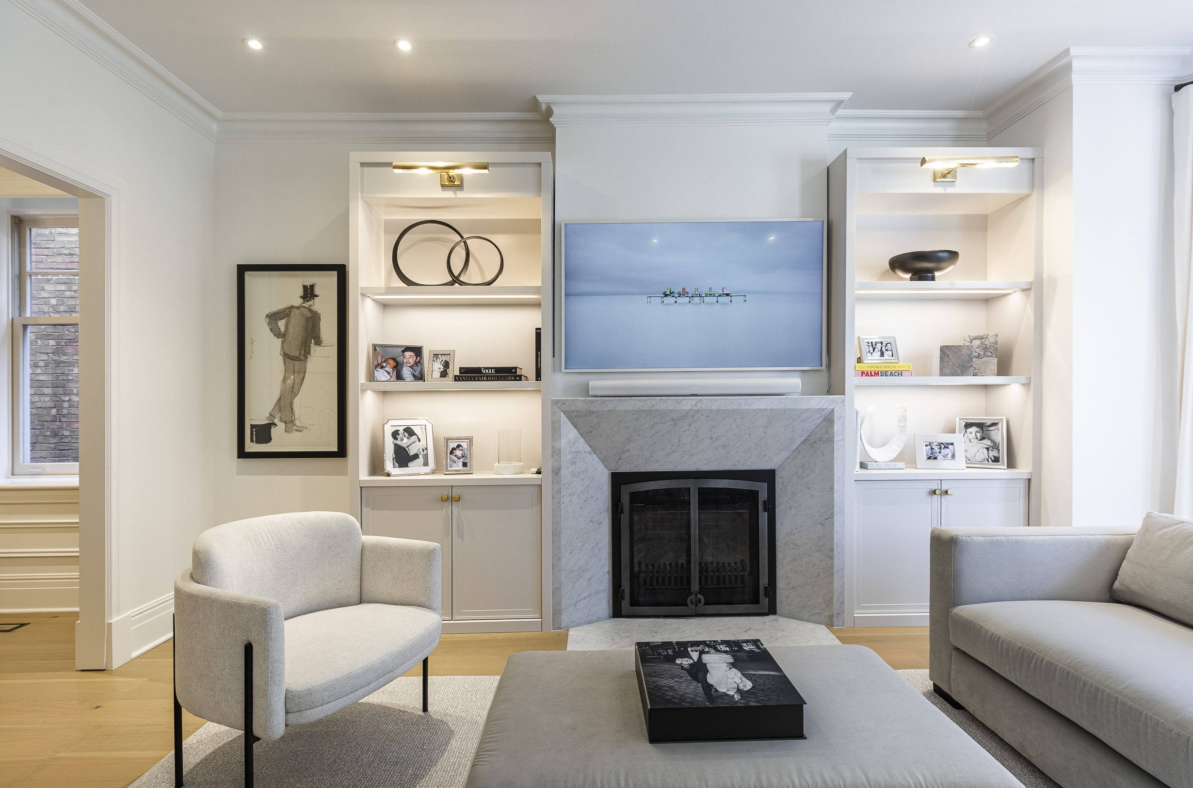 Experience modern elegance in this light-filled living room featuring a cozy gray sofa, sleek black coffee table, and stylish built-in shelving.