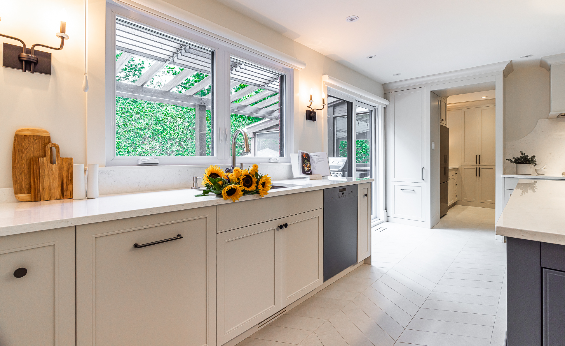 Modern kitchen with light cream cabinetry, spacious countertop, and vibrant sunflowers for a cheerful touch.