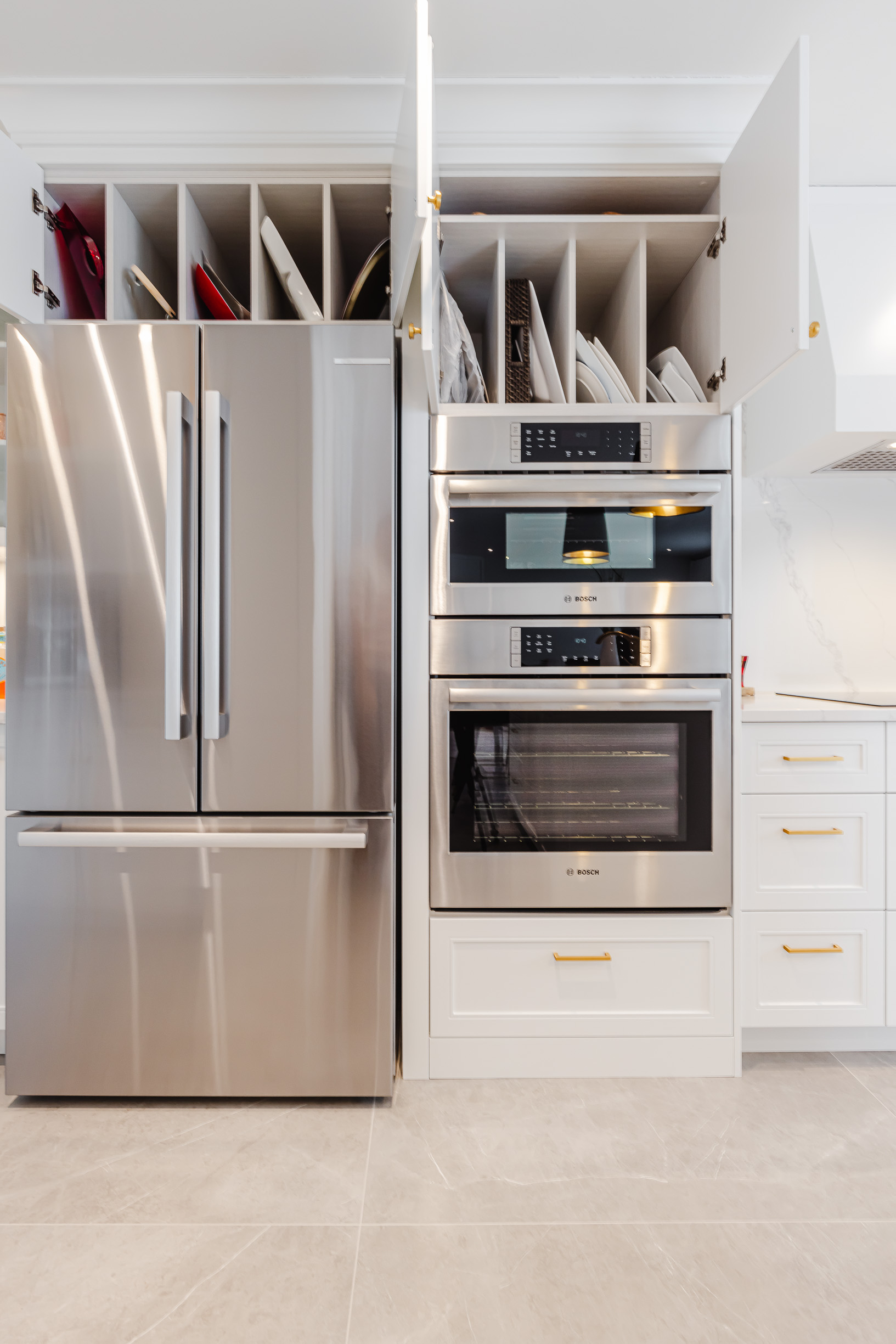 Modern kitchen showcasing stainless steel appliances, warm light wood cabinetry, and stylish tile flooring for a functional, inviting cooking space.