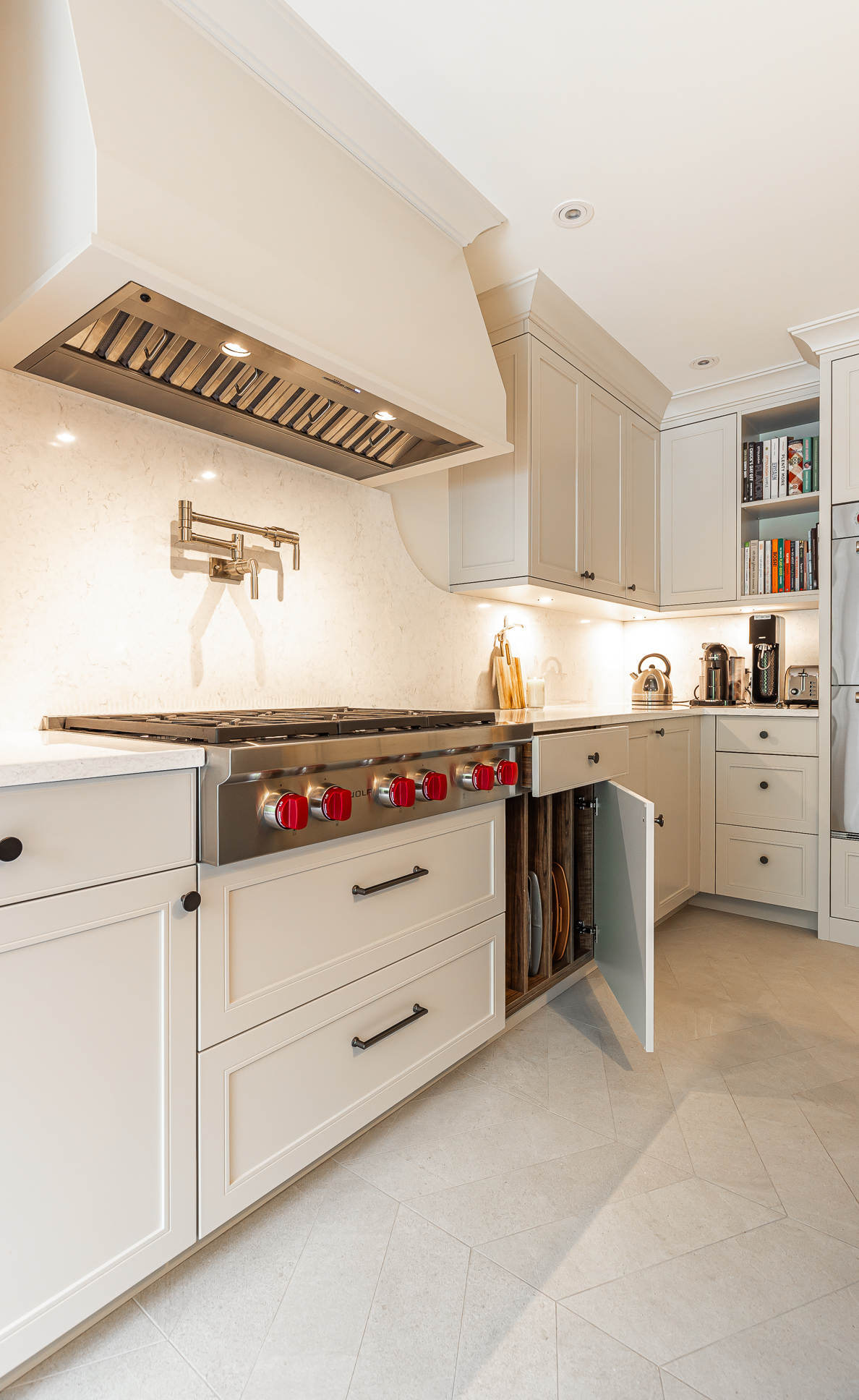 Modern kitchen with elegant design, creamy palette, red-accented stove, and functional open shelves.