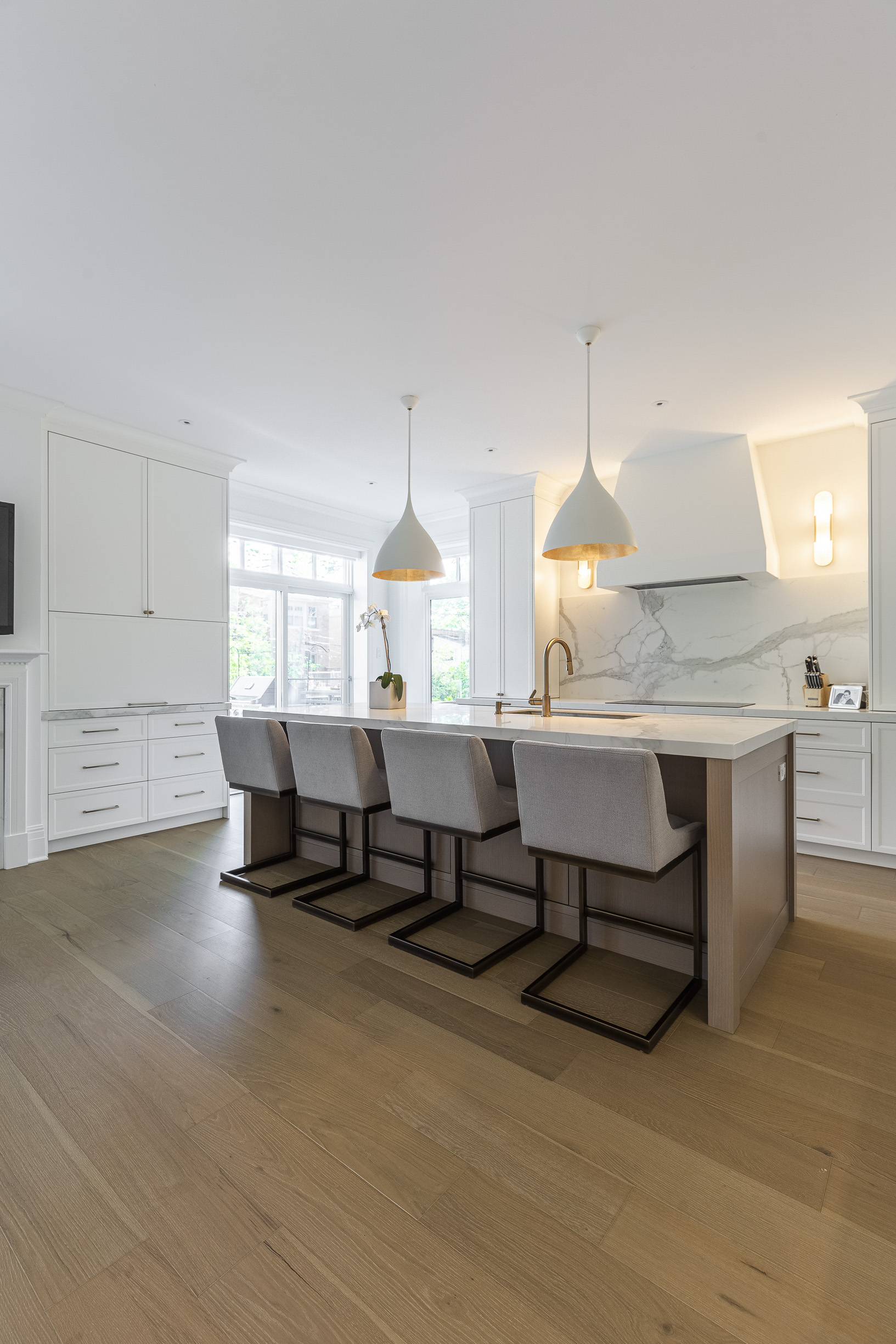 Modern kitchen featuring a sleek marble island, stylish pendant lights, and natural light for inviting gatherings and cooking.