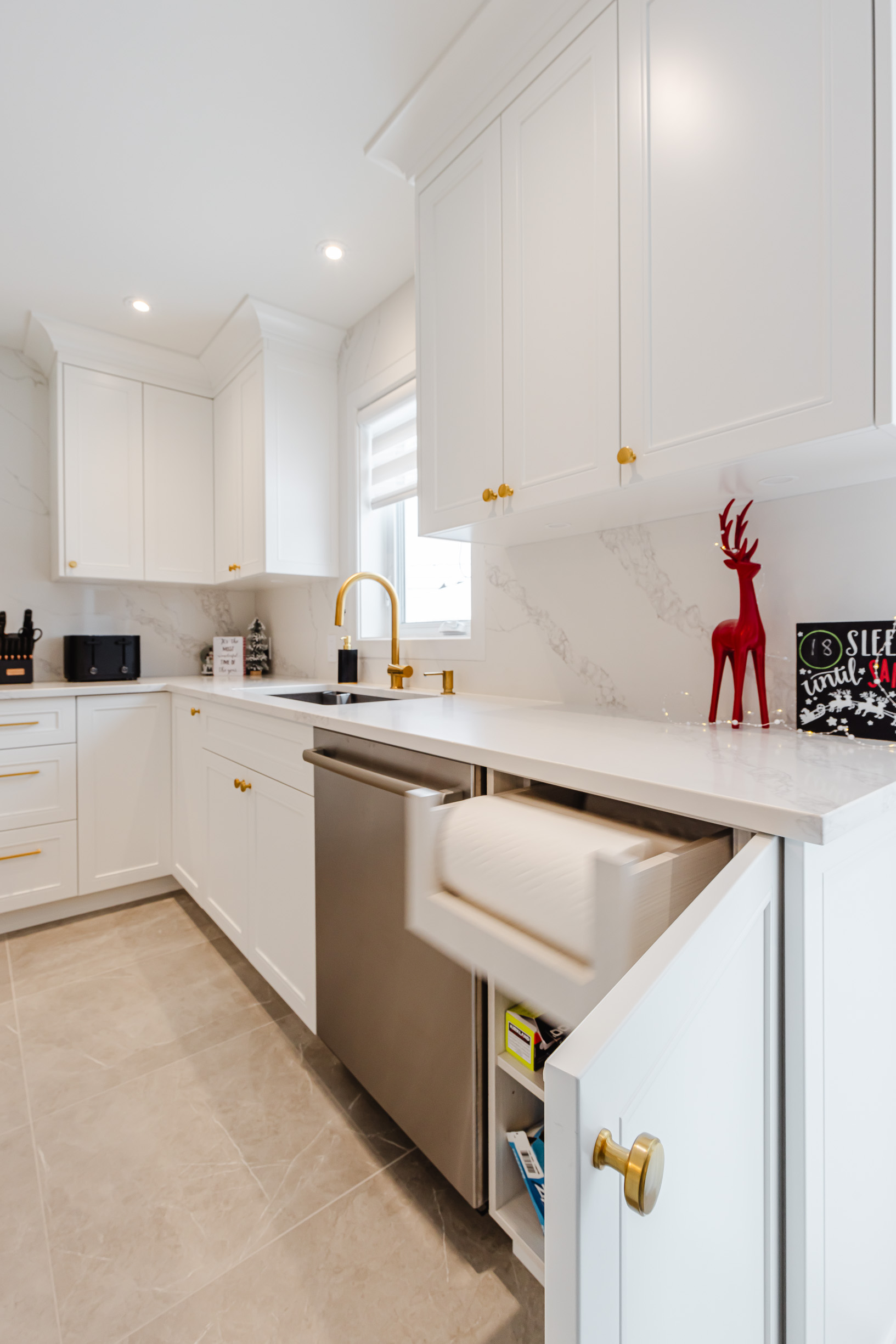 Modern white kitchen with gold accents, stainless steel sink, and festive decor for a chic look.