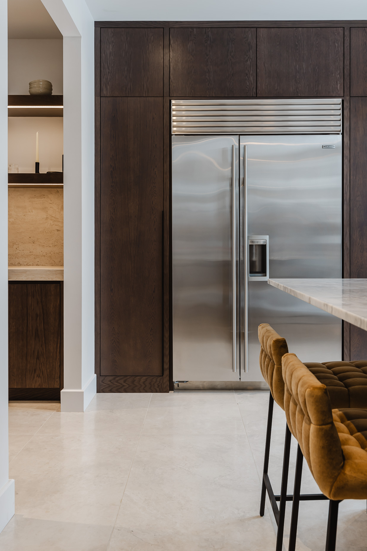 Discover a sleek modern kitchen featuring a stainless steel refrigerator, dark cabinetry, and inviting island seating for stylish gatherings.
