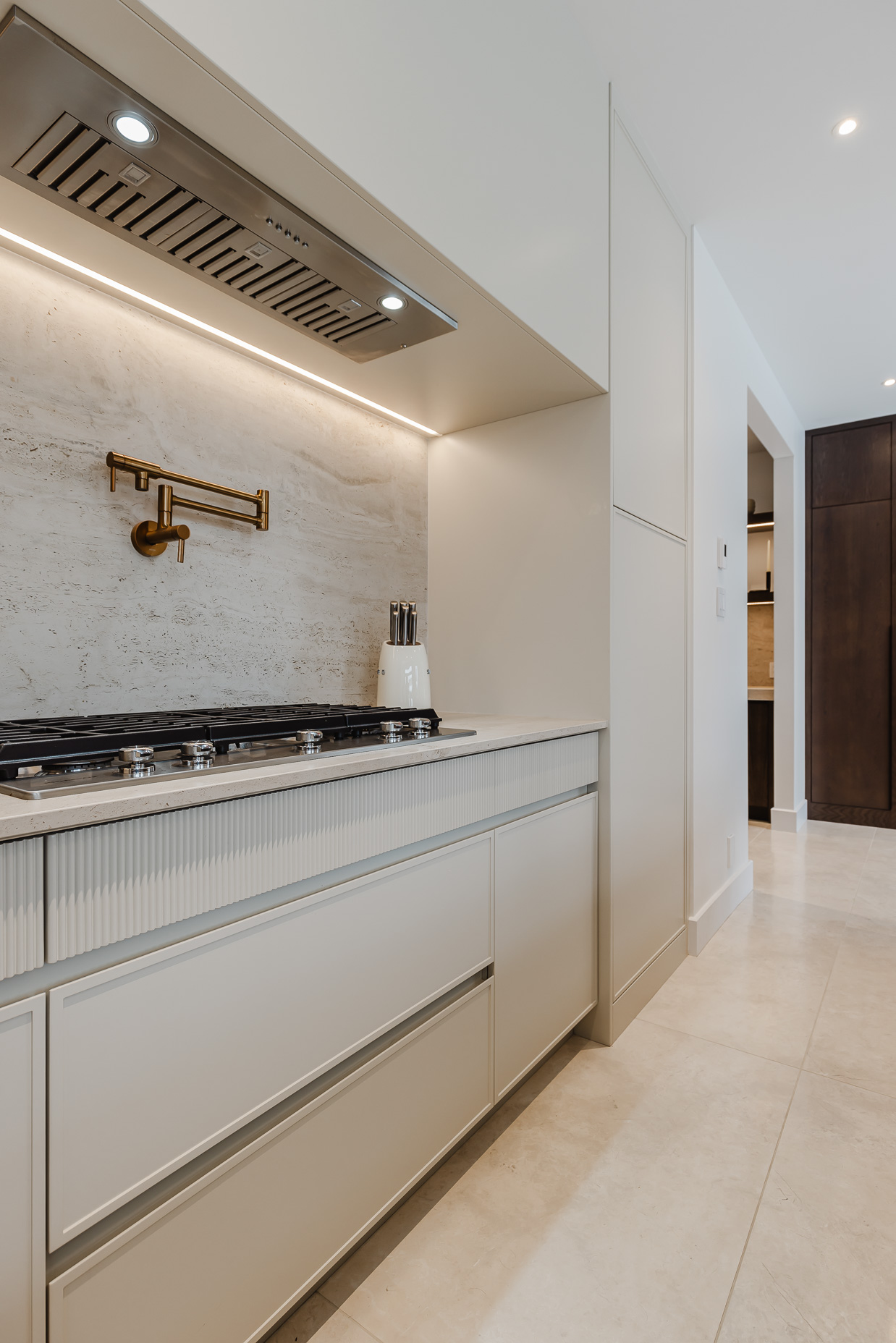 Modern kitchen featuring cream cabinetry, a sleek gas cooktop, and elegant brass accents for a stylish and functional cooking space.