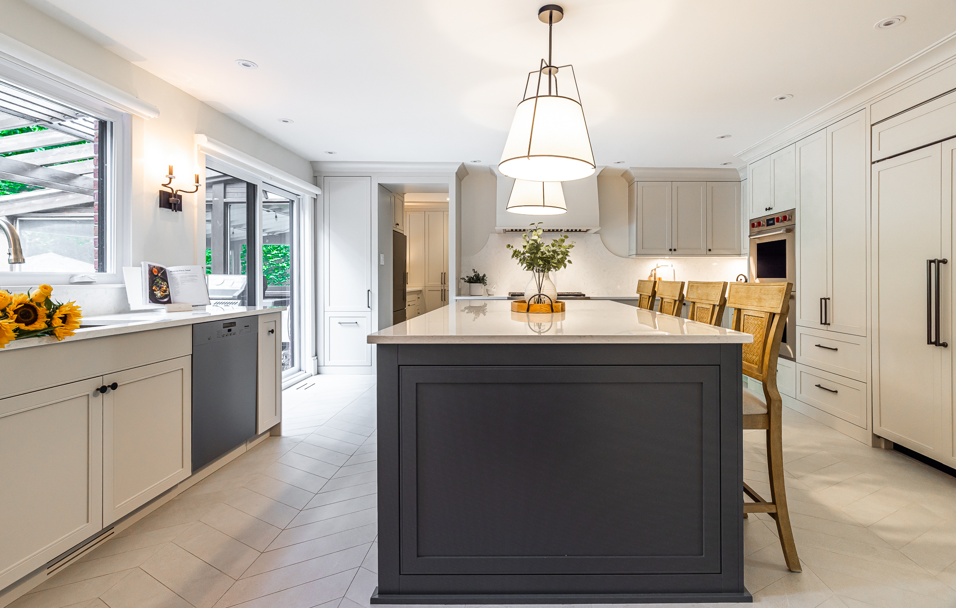A stylish modern kitchen with a gray island, white countertop, and wooden stools invites warmth and light for cooking and entertaining.