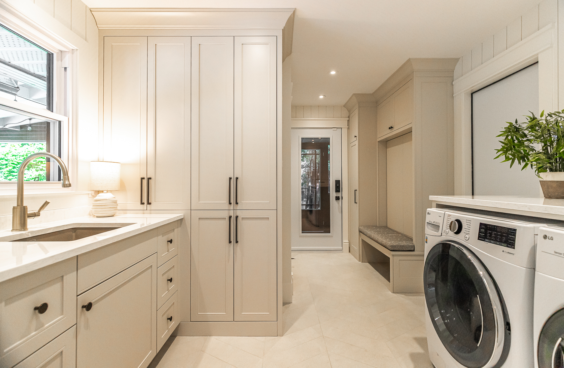 Discover a stylish modern laundry room featuring elegant cabinetry, a functional sink, and a cozy nook for added convenience.
