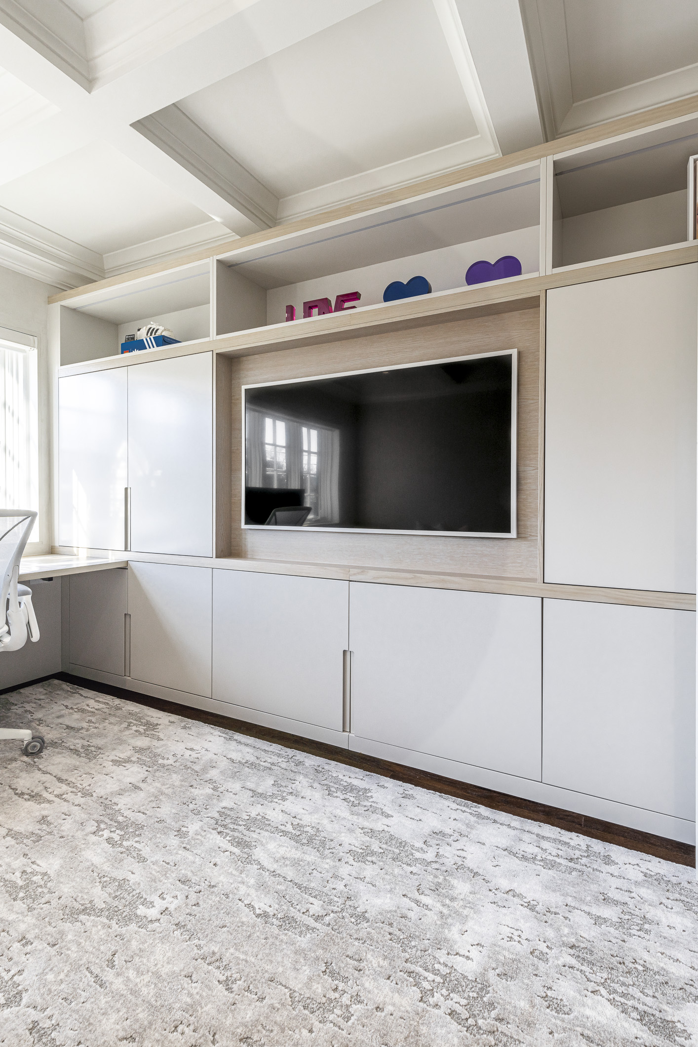 Sleek minimalist living room featuring a white entertainment center, vibrant decor, and a functional workspace for ultimate relaxation and productivity.