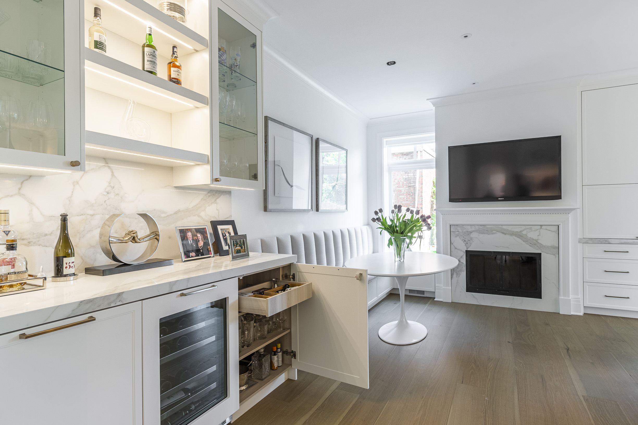 Bright and sophisticated modern living space featuring an elegant dining area, stylish cabinetry, and a cozy fireplace for warmth and charm.