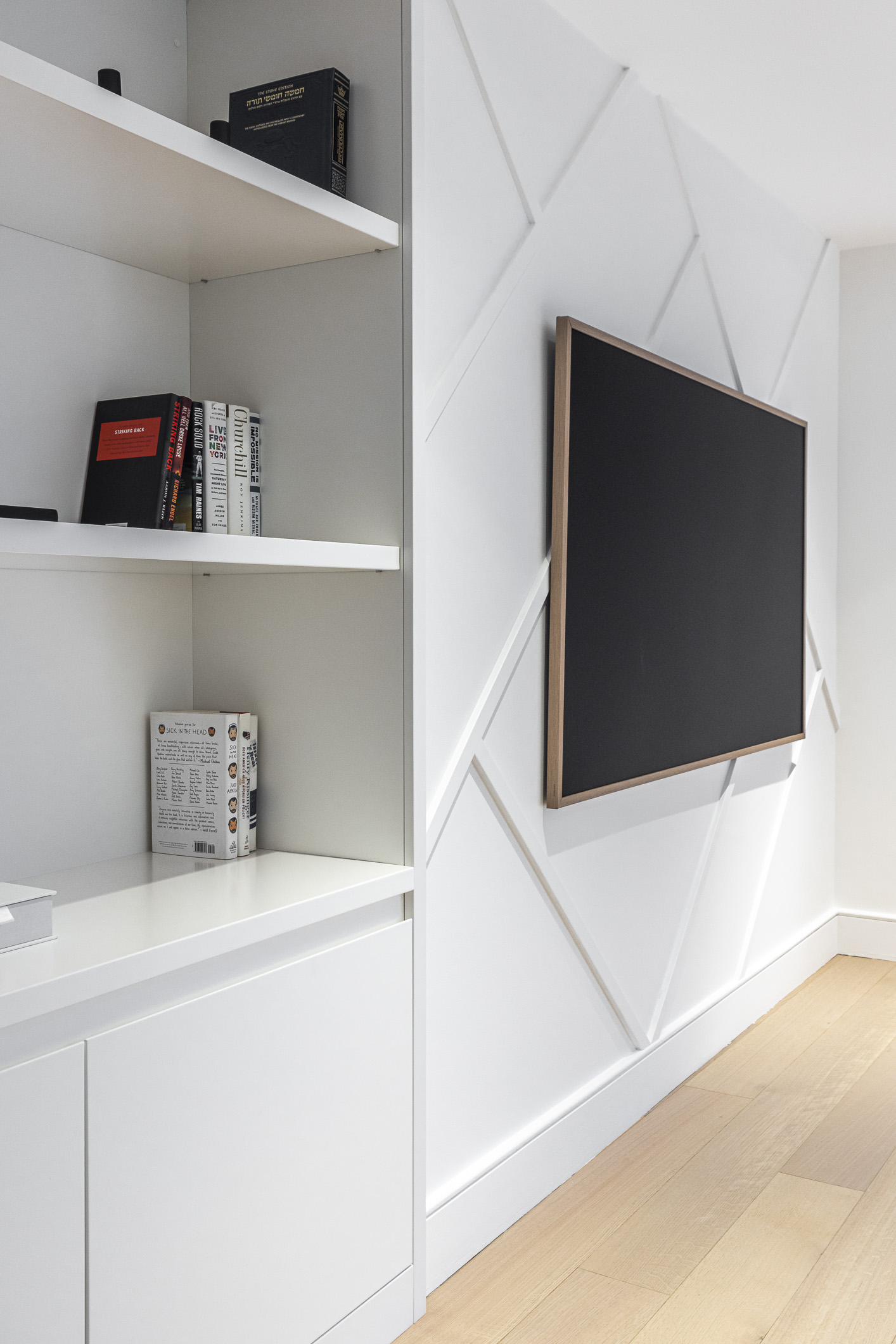 Discover a sophisticated modern media wall with geometric patterns, minimalist decor, and a sleek flat-screen TV, complemented by warm wood flooring.