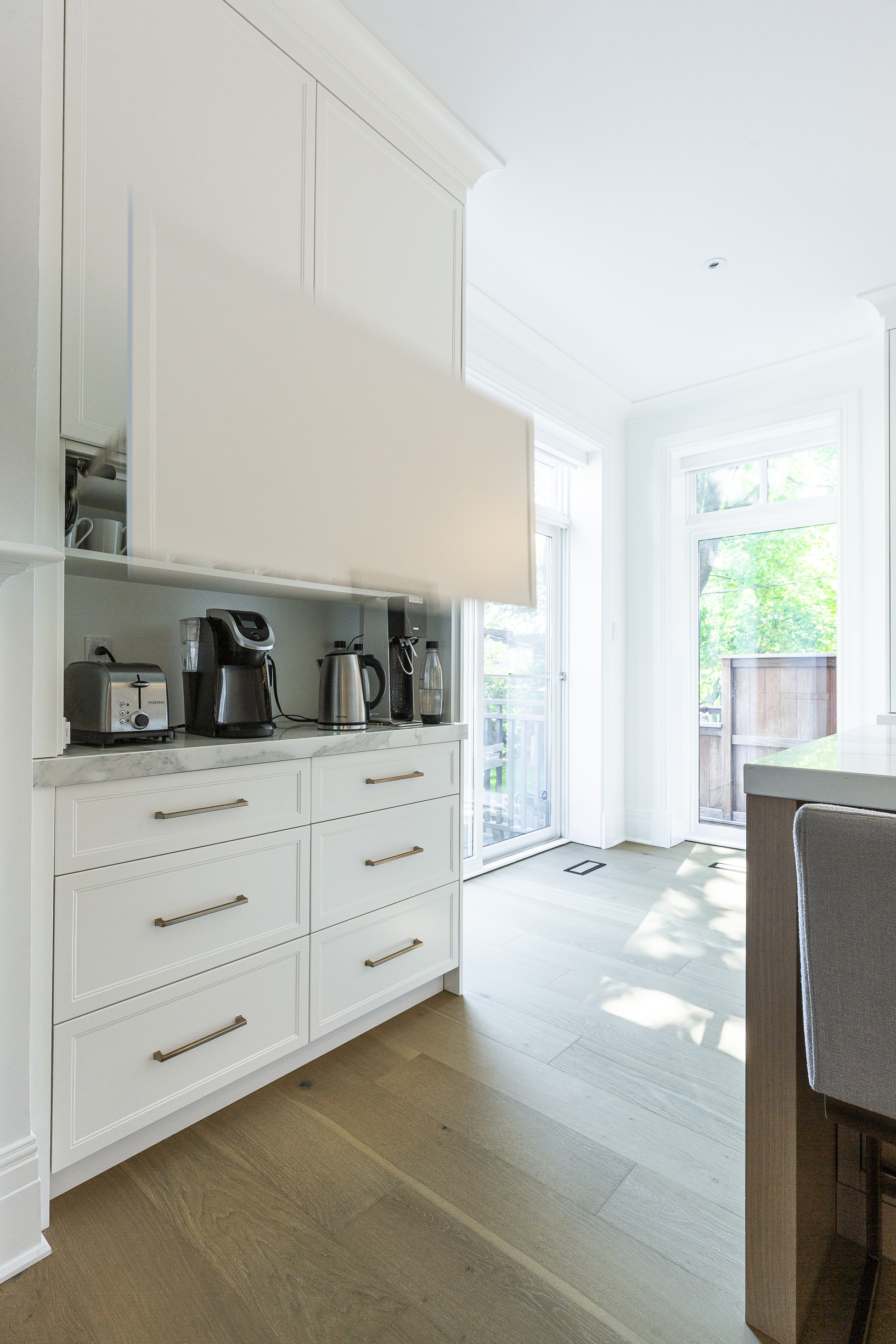 Bright and airy modern kitchen featuring sleek white cabinetry, natural light, and a cozy bar area for casual dining.