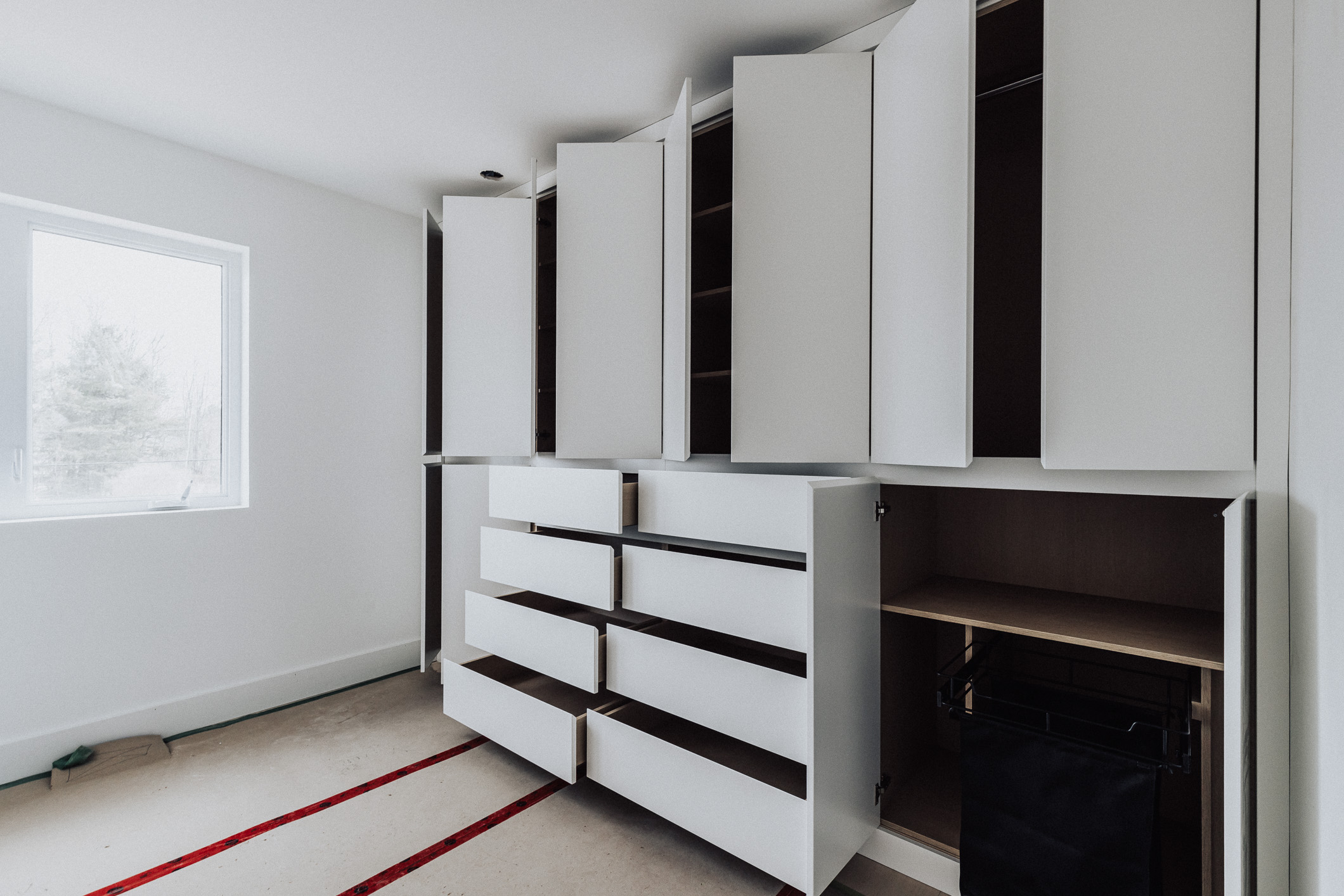 Sleek white cabinetry with staggered heights enhances the bright, airy room, complemented by warm carpet accents and natural light.