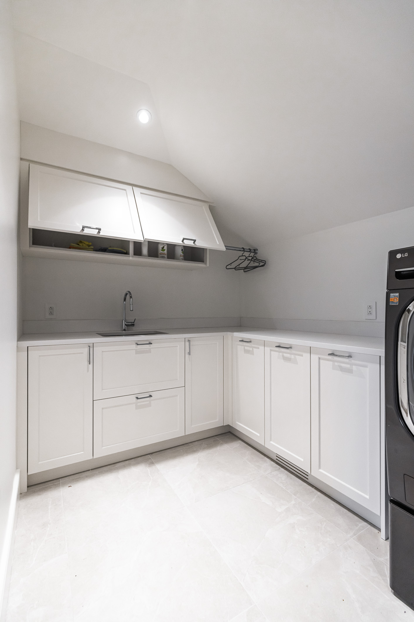 Sleek and functional, this modern laundry room features white cabinetry, a stainless steel washer, and organized shelves for an uncluttered space.