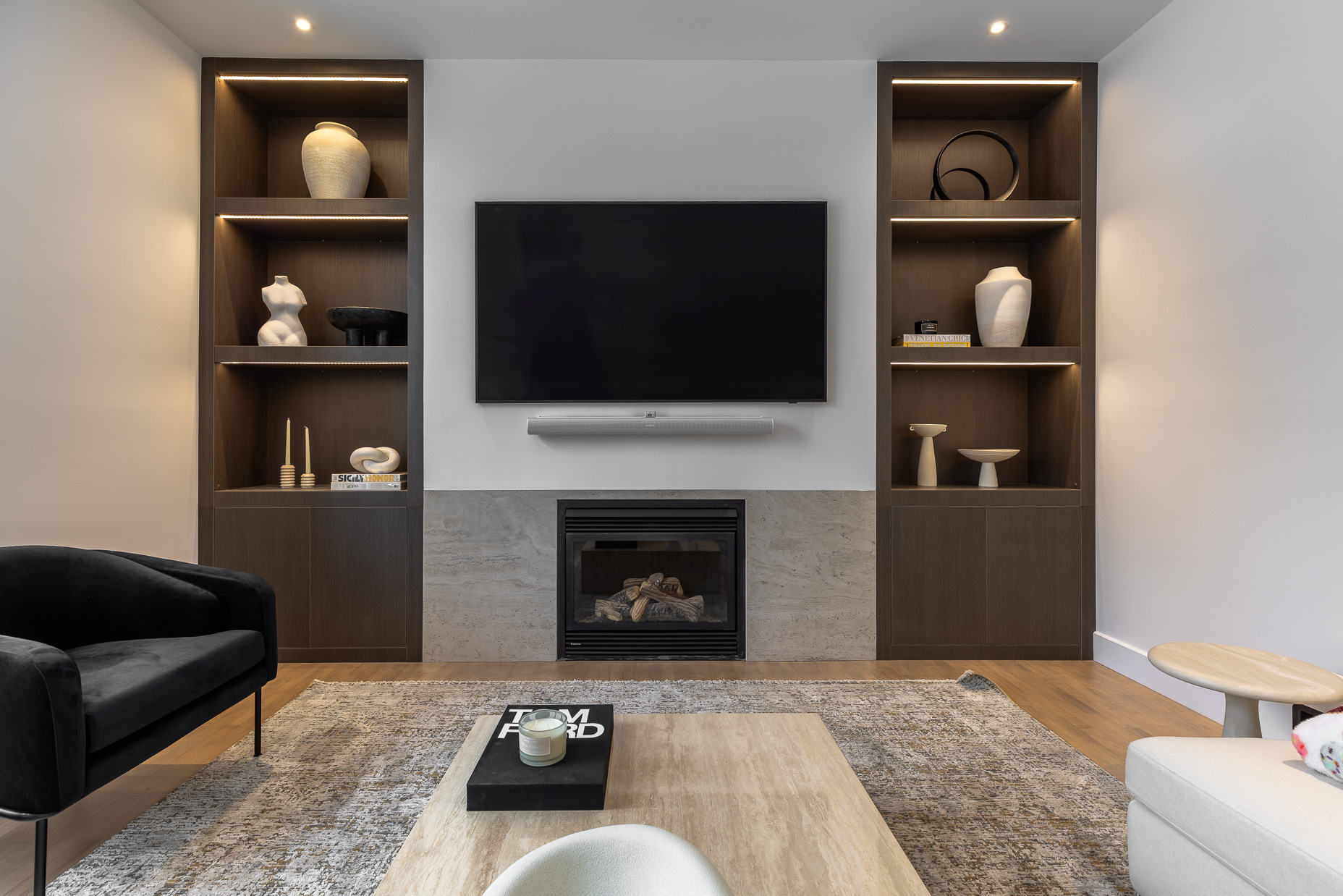 Modern minimalist living room featuring a flat-screen TV, electric fireplace, and stylish decor, creating an inviting and serene atmosphere.