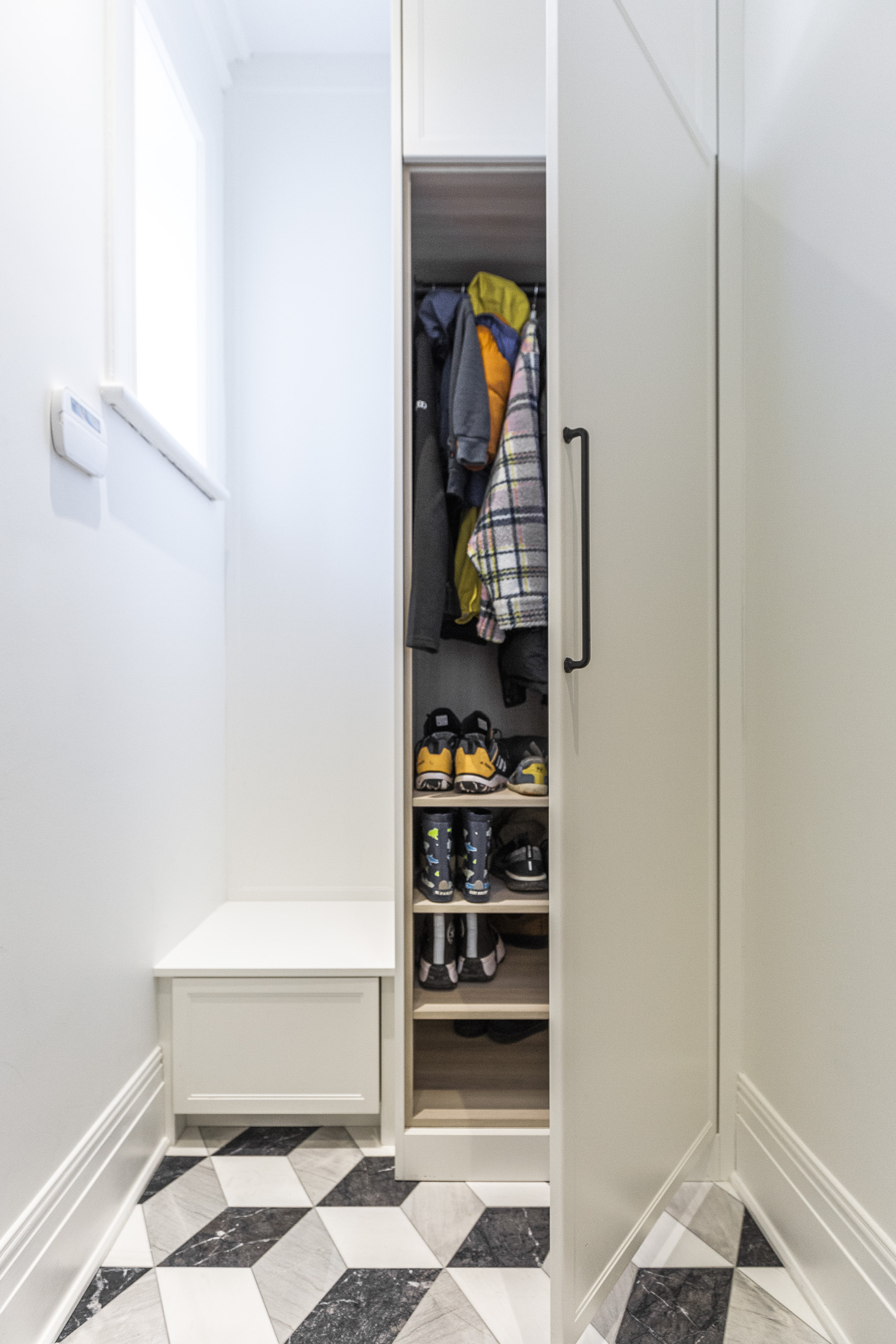 Discover a sleek, organized closet with vibrant clothing and a functional bench, ideal for a modern and efficient entryway.