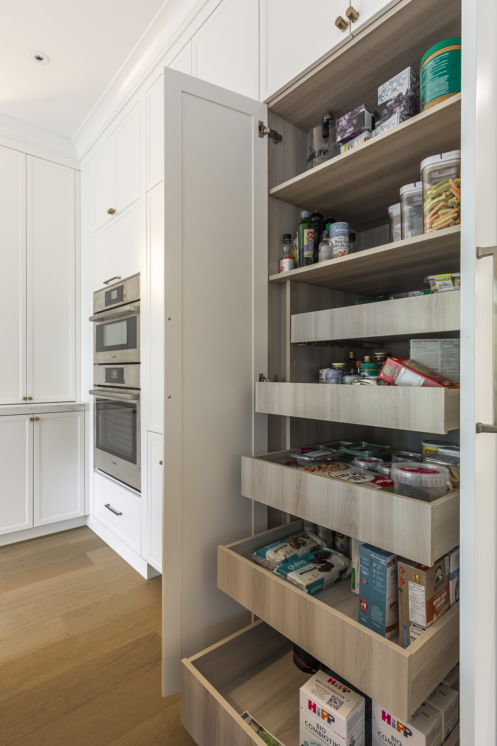 A beautifully organized modern pantry with clear containers and light wood shelves enhances kitchen efficiency and style.