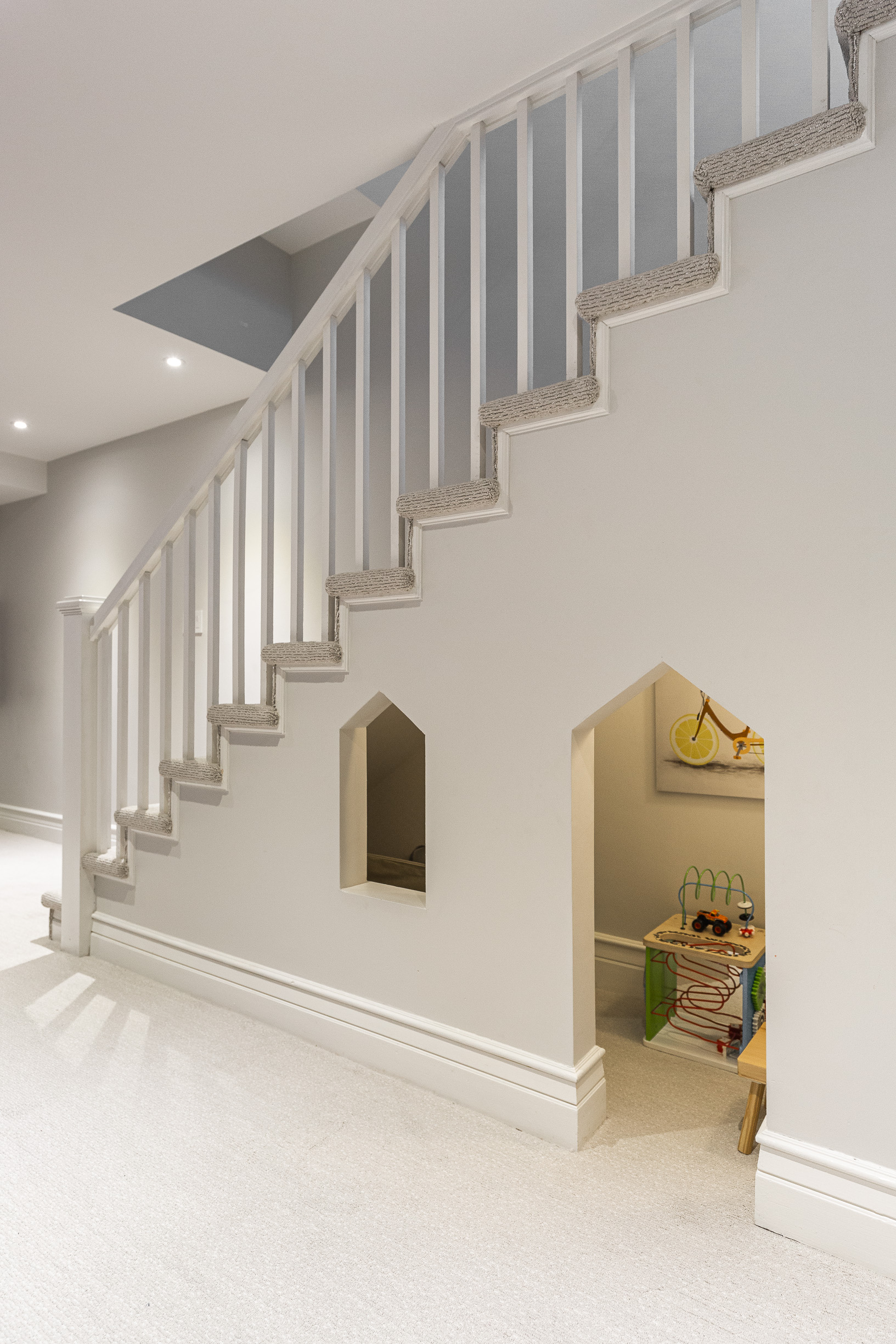 Sleek white staircase with a playful kids nook underneath creates a perfect blend of style and functionality in this modern interior.