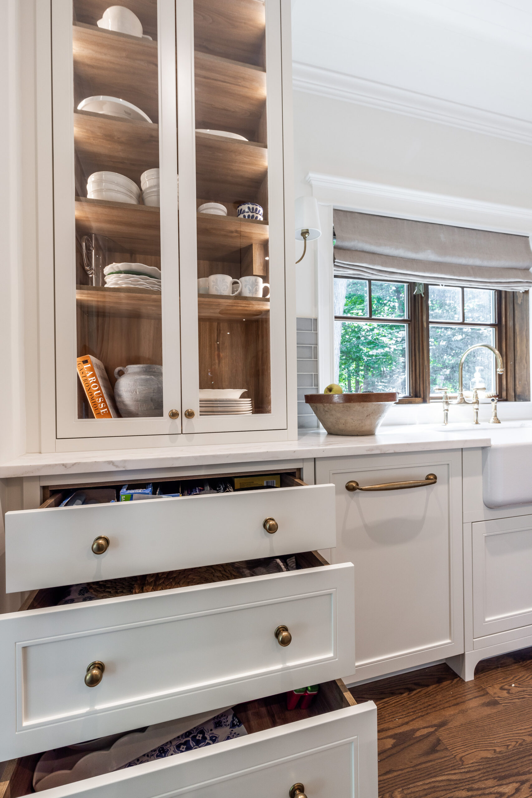 Bright and inviting kitchen featuring elegant white cabinetry, gold accents, and warm wooden floors that enhance the natural light.
