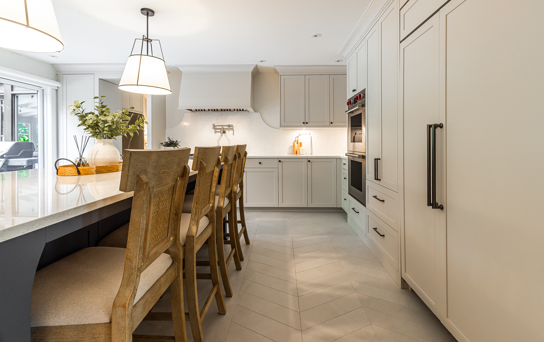 A modern kitchen featuring warm tones, a cozy island with wooden seating, and abundant natural light creates an inviting cooking and gathering space.