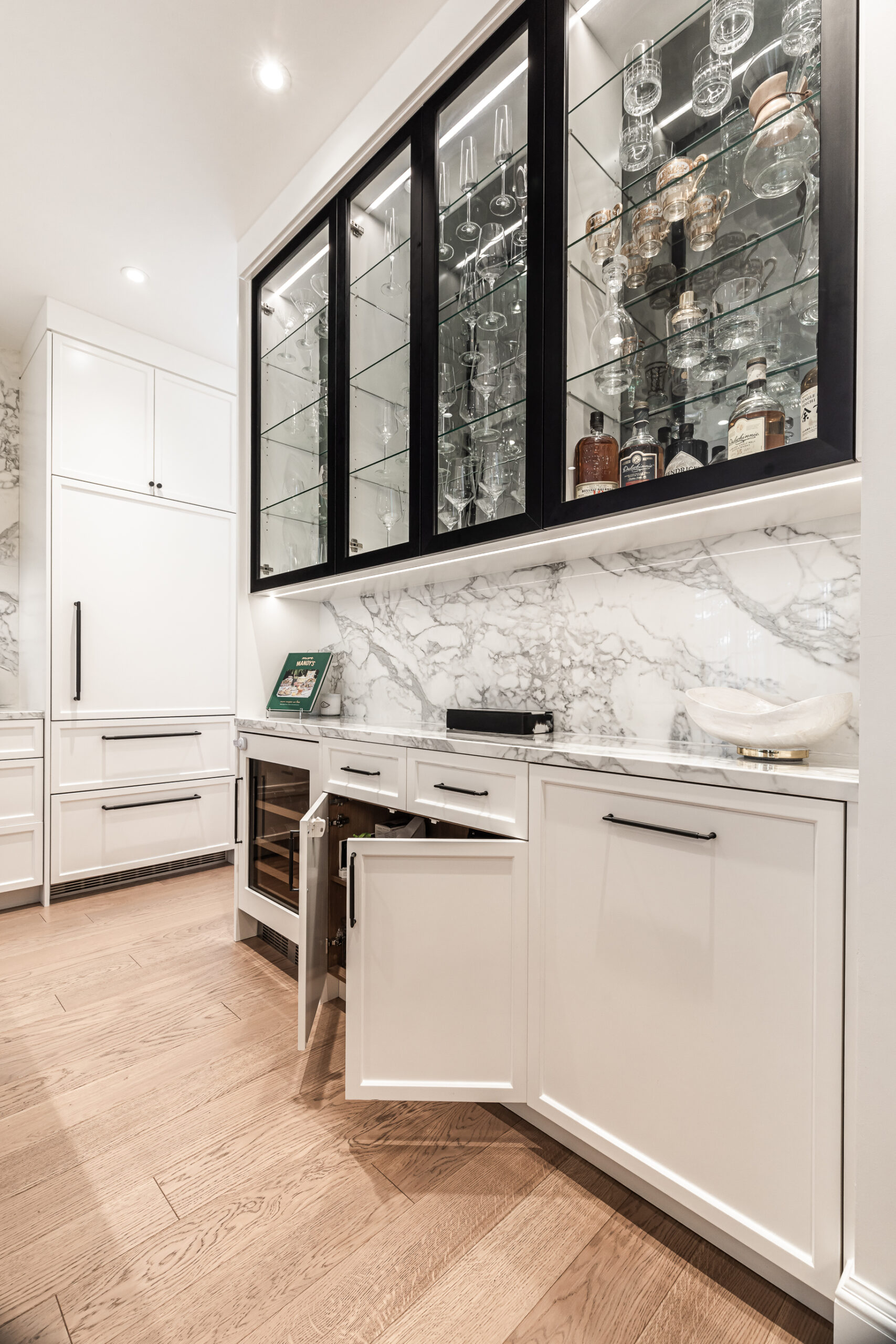 Sophisticated modern kitchen featuring white cabinetry, luxurious marble accents, and warm wooden flooring for an inviting atmosphere.